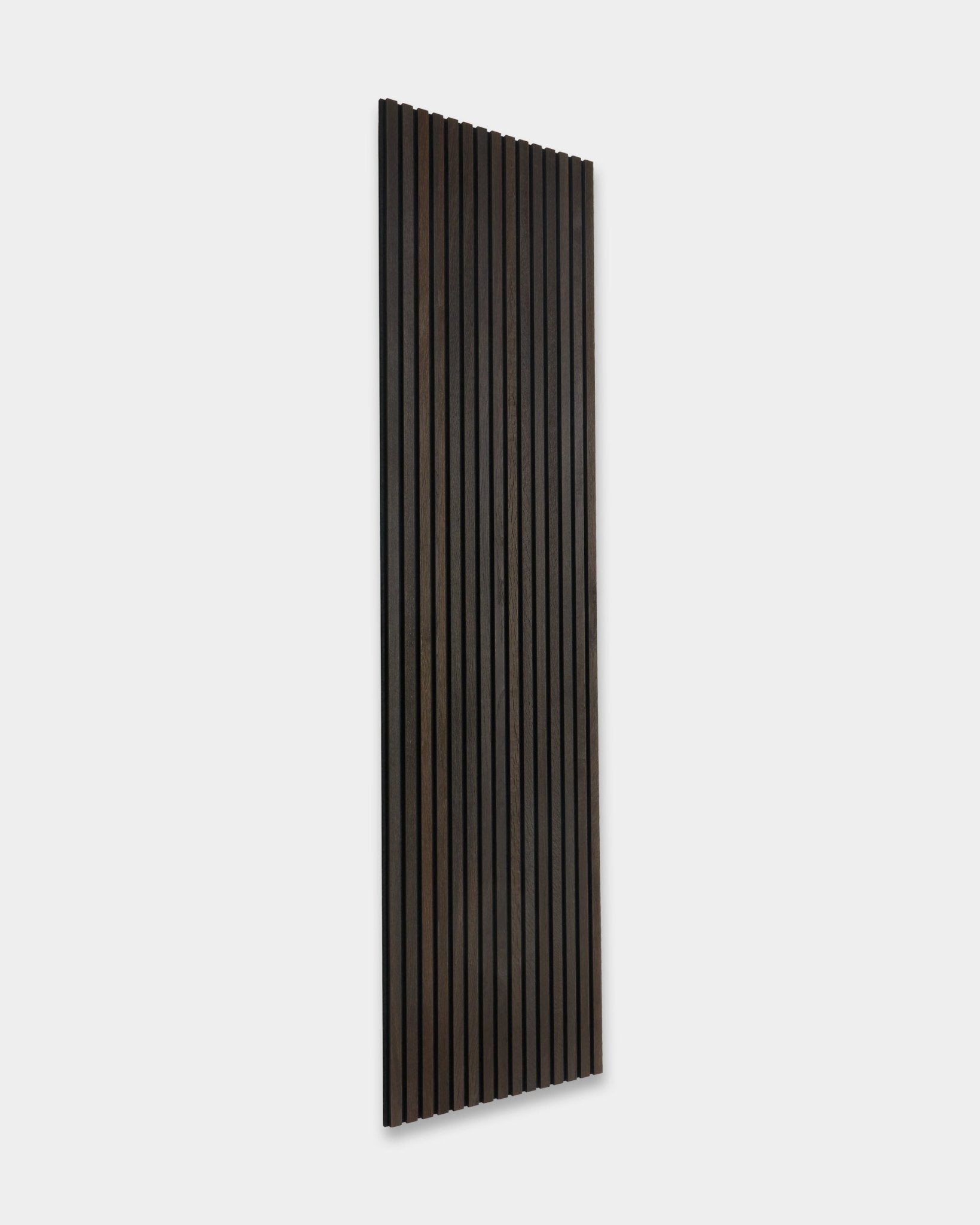 Rustic Smoked Oak Akupanel Panel akustyczny od WoodUpp, z ciemnymi drewnianymi lamelami vertical, oparty o jasnoszarą ścianę.