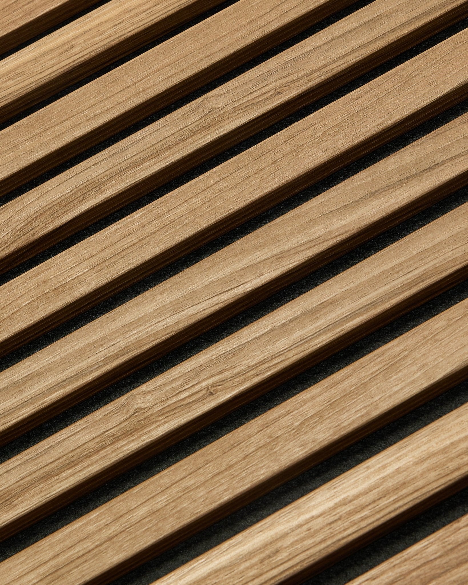 Ujęcie z bliska pod skosem panelu WoodUpp Akupanel Essential Panel akustyczny w kolorze English Walnut, 240x60 cm, pokazujące jednolite wykończenie i ciemne tło między każdą drewnianą lamelą.