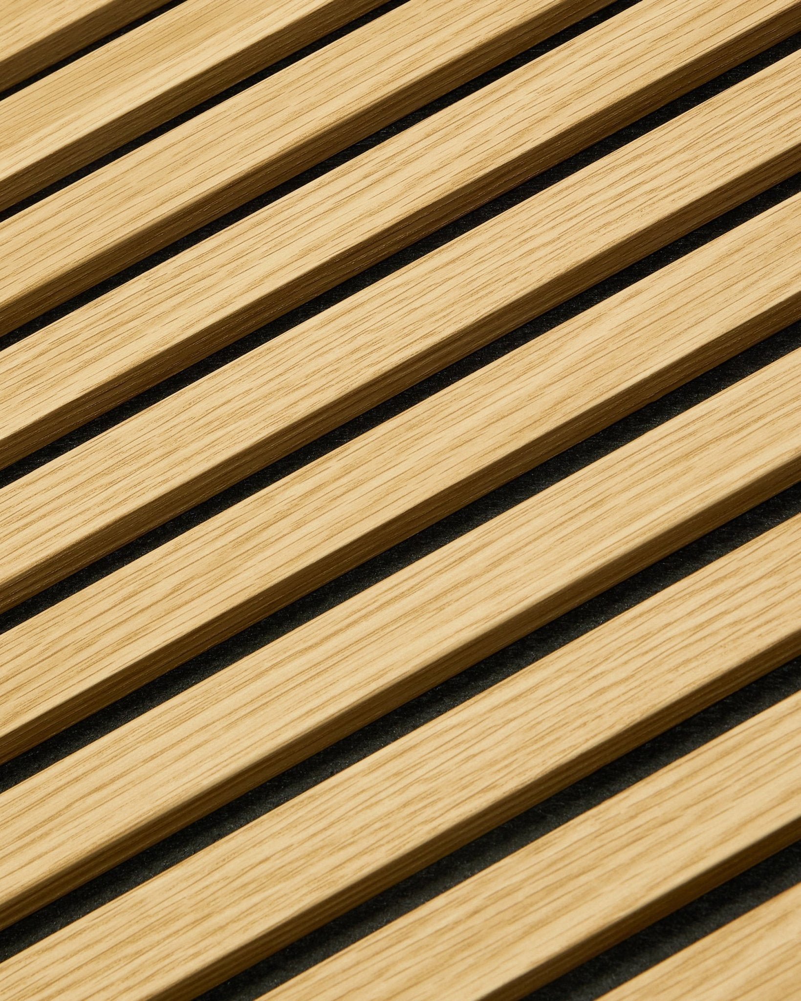 Zbliżenie na WoodUpp Akupanel Panel akustyczny w kolorze Southern Oak, 240 x 60 cm, z ukośnymi lamelami i ciemnymi szczelinami akustycznymi, które poprawiają pochłanianie dźwięku.