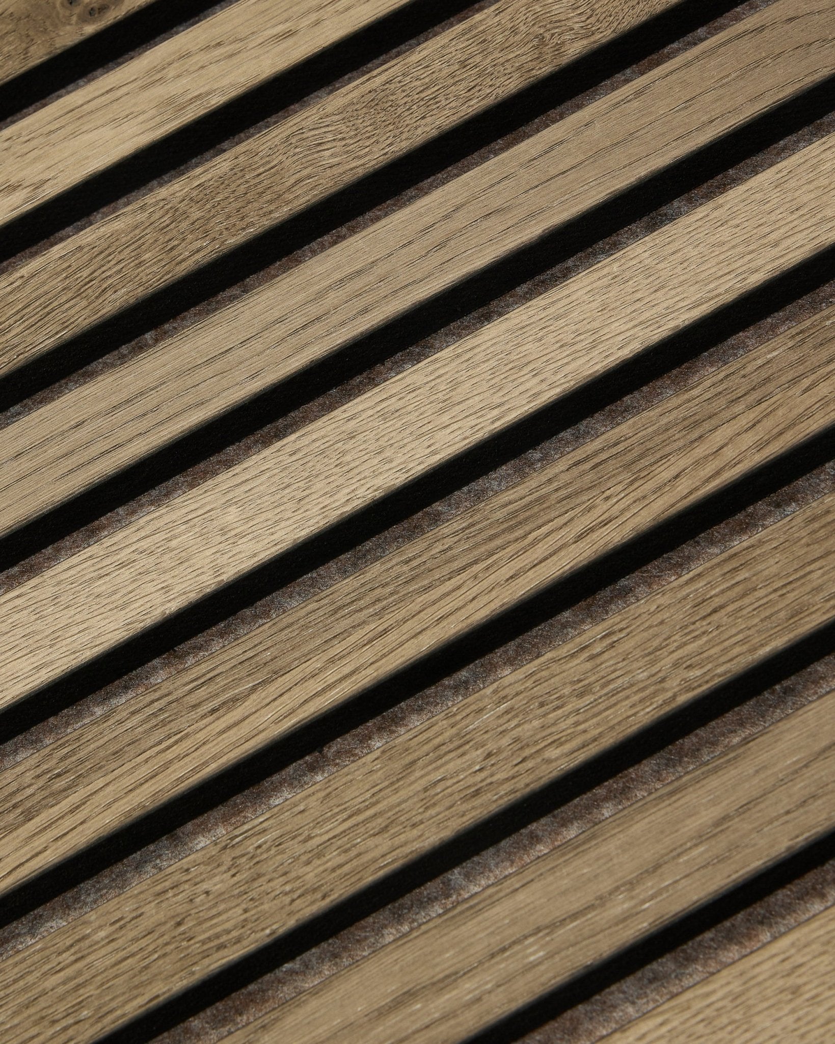 Zbliżenie na WoodUpp Tonal Akupanel Panel akustyczny w kolorze Grey Oak (240x60 cm), pokazujące równomiernie rozmieszczone ukośne lamele z usłojeniem natural oak i w nordyckim stylu.