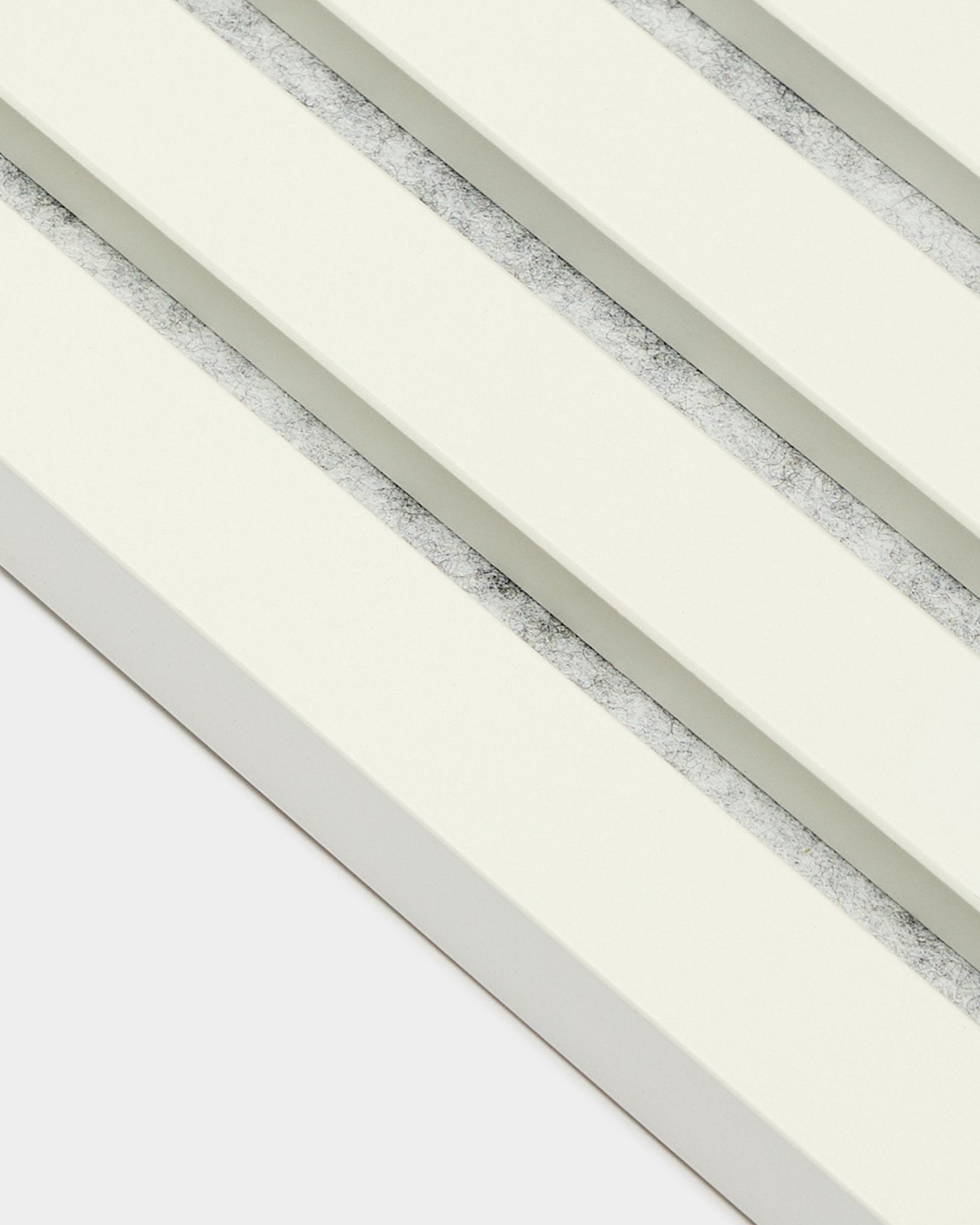 Cztery panele akustyczne WoodUpp Akupanel End Lamella/Snow (2,2 cm), ułożone po przekątnej, z lamelami w odcieniu złamanej bieli i teksturowanymi szarymi przerwami, w nordyckim stylu.