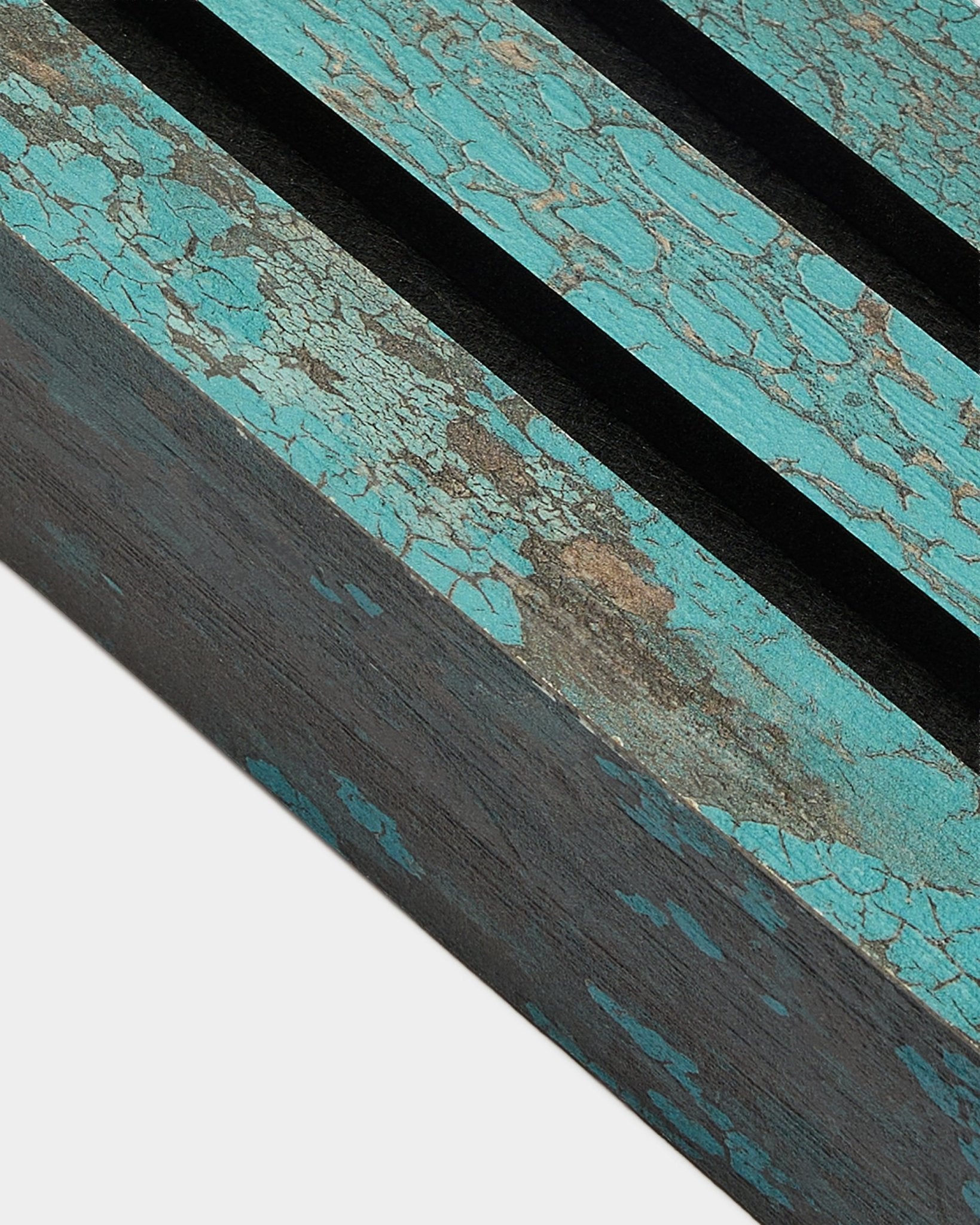 Zbliżenie końcowej lameli WoodUpp Akupanel w kolorze Oxide Blue, o szerokości 6,7 cm, z popękaną niebieską farbą i rowkami black na rustykalnej powierzchni Panel akustyczny.