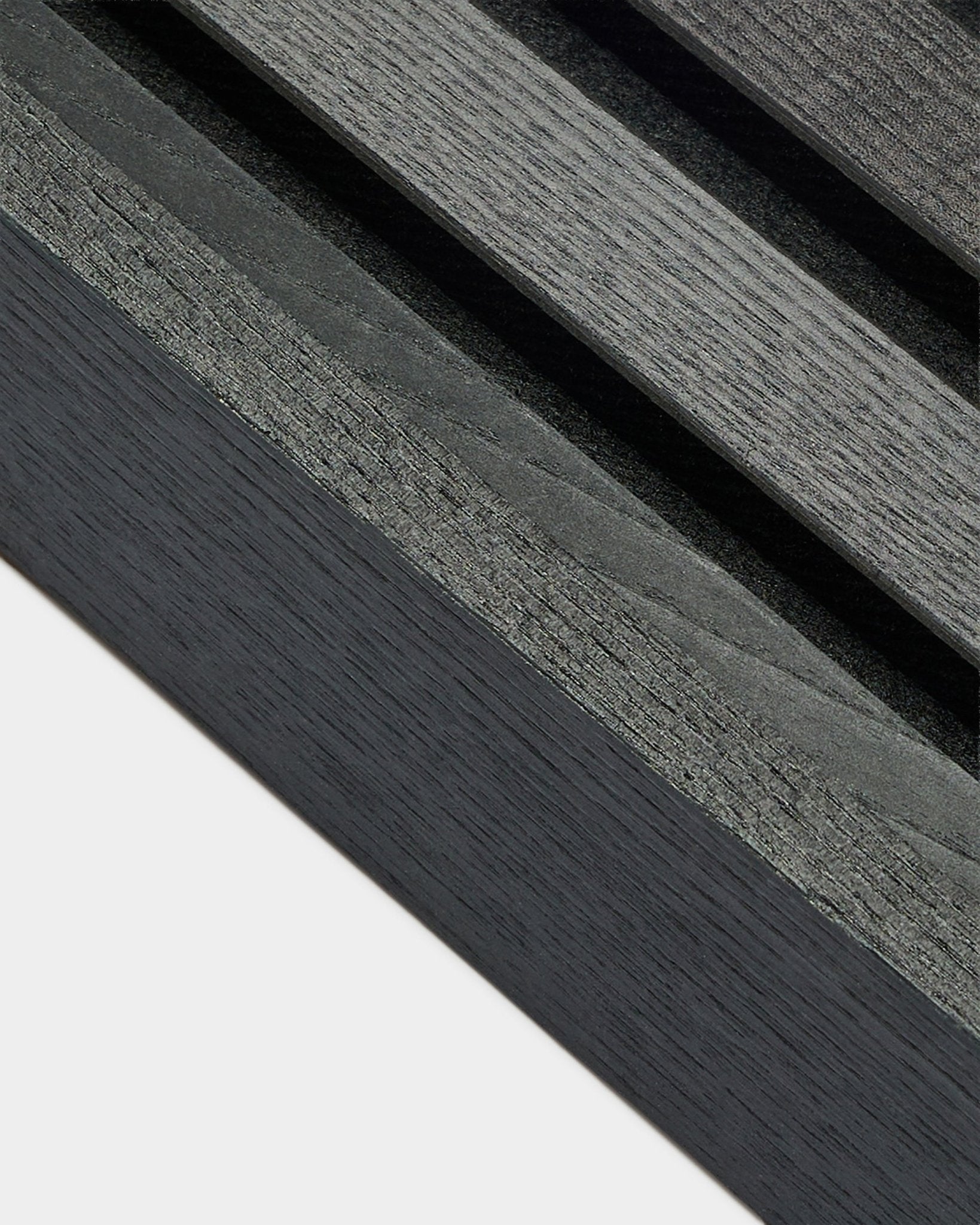 Zbliżenie na lamelę końcową WoodUpp Akupanel w kolorze Black Ash (6,7 cm), ukazujące ciemnoszare usłojenie drewna na jasnej bazie, zaprojektowaną z myślą o nordyckich aranżacjach Panel akustyczny.