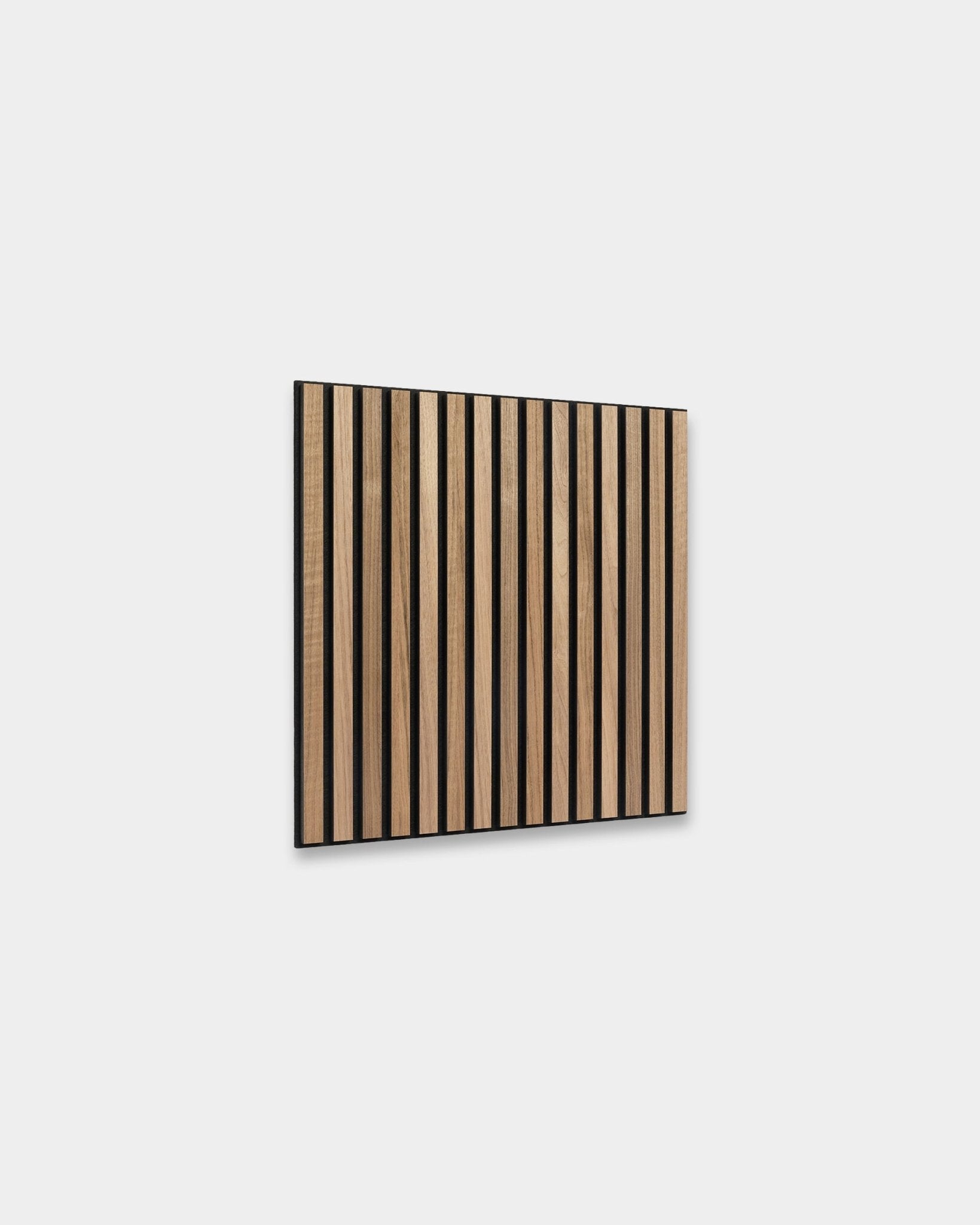 WoodUpp Akupixel Panel akustyczny w kolorze orzecha, 60x60 cm, ma równomiernie rozmieszczone lamele z orzecha z przerwami black, zamontowane na jasnoszarej ścianie, w skandynawskim stylu.