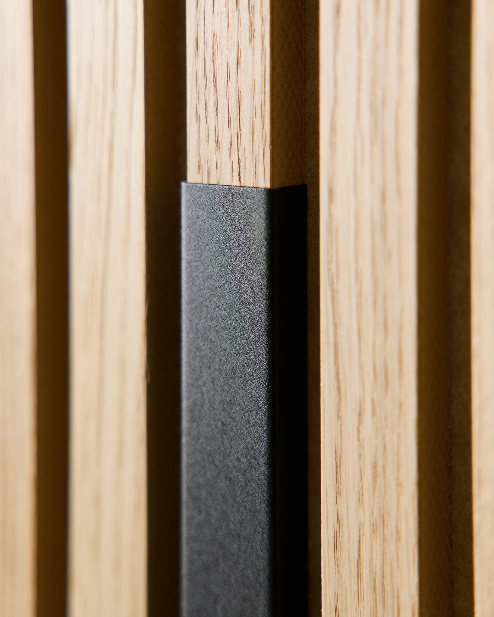 Zbliżenie na WoodUpp Liva Panel akustyczny z 60-centymetrową osłoną aluminiową black, ukazujące drewniane lamele vertical i akcent black do nowoczesnych wnętrz w stylu nordyckim.