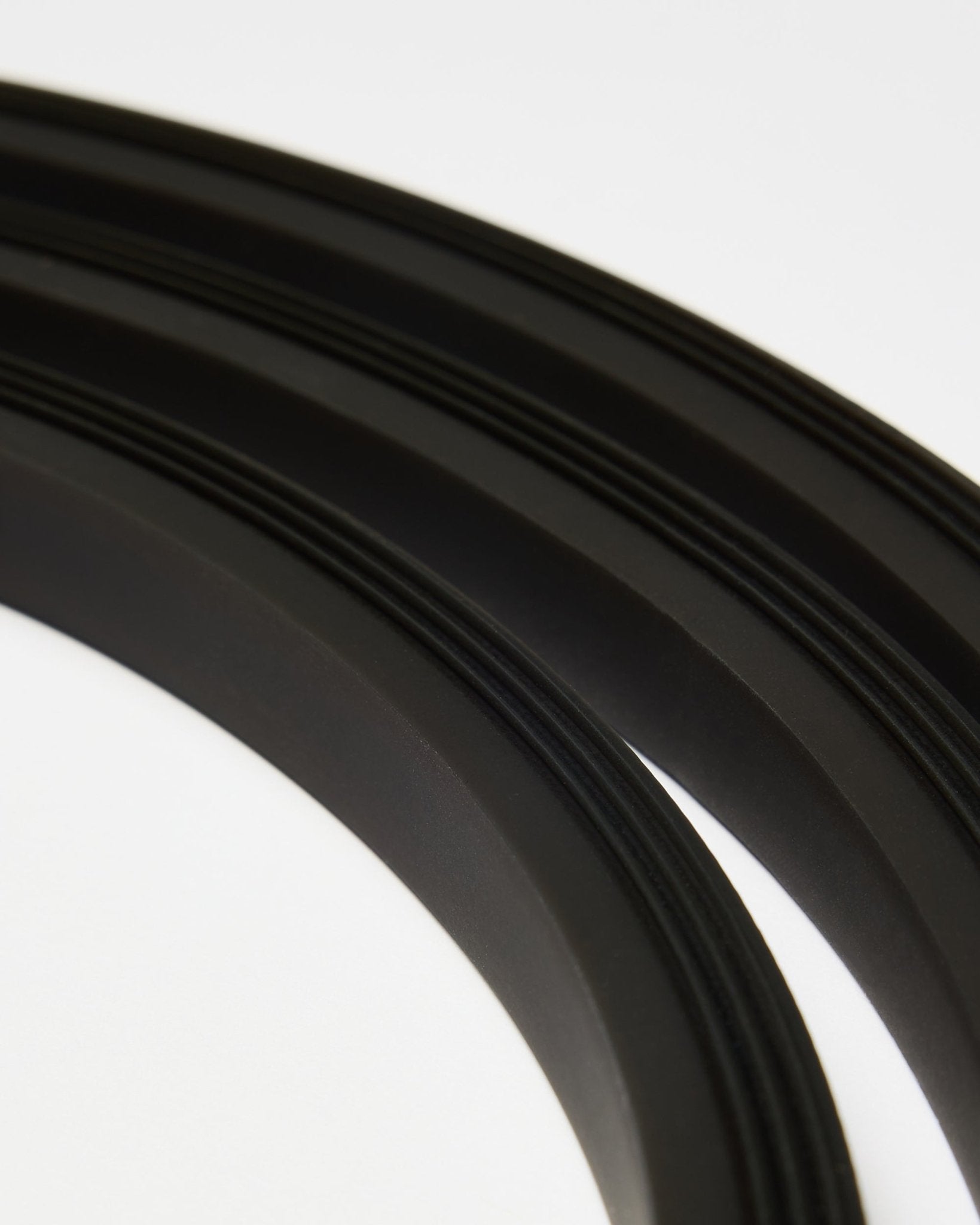 Zbliżenie na taśmę LED WoodUpp black Lumi (300 cm), ułożoną w zakrzywione linie na białym tle, dopełniającą minimalistyczny styl Akupanel Panel akustyczny.