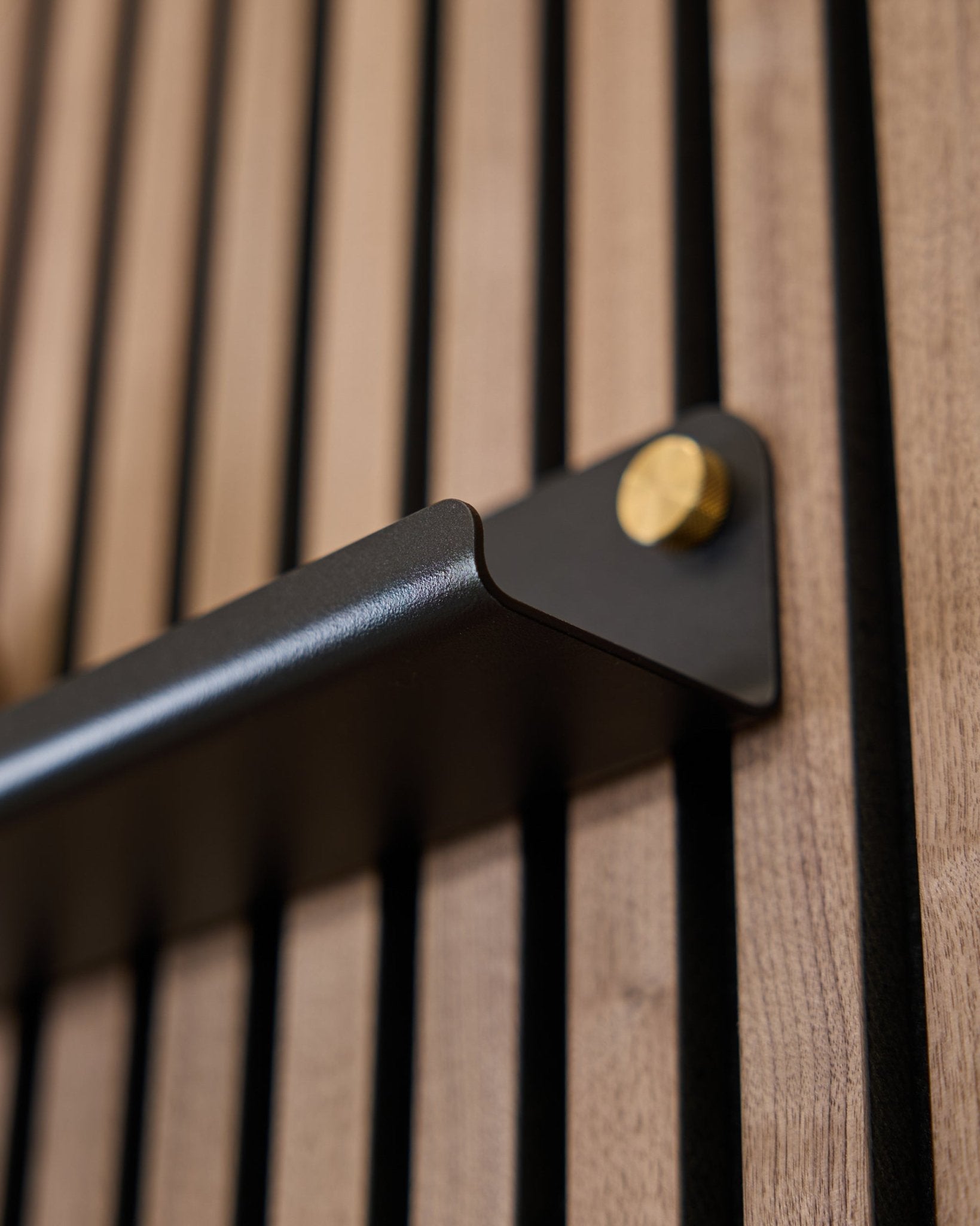 Zbliżenie na Norr | wąską półkę (75,9 cm) od WoodUpp w kolorze black, z uchwytem steel i złotymi śrubami oraz pionowo ryflowaną powierzchnią akustyczną.