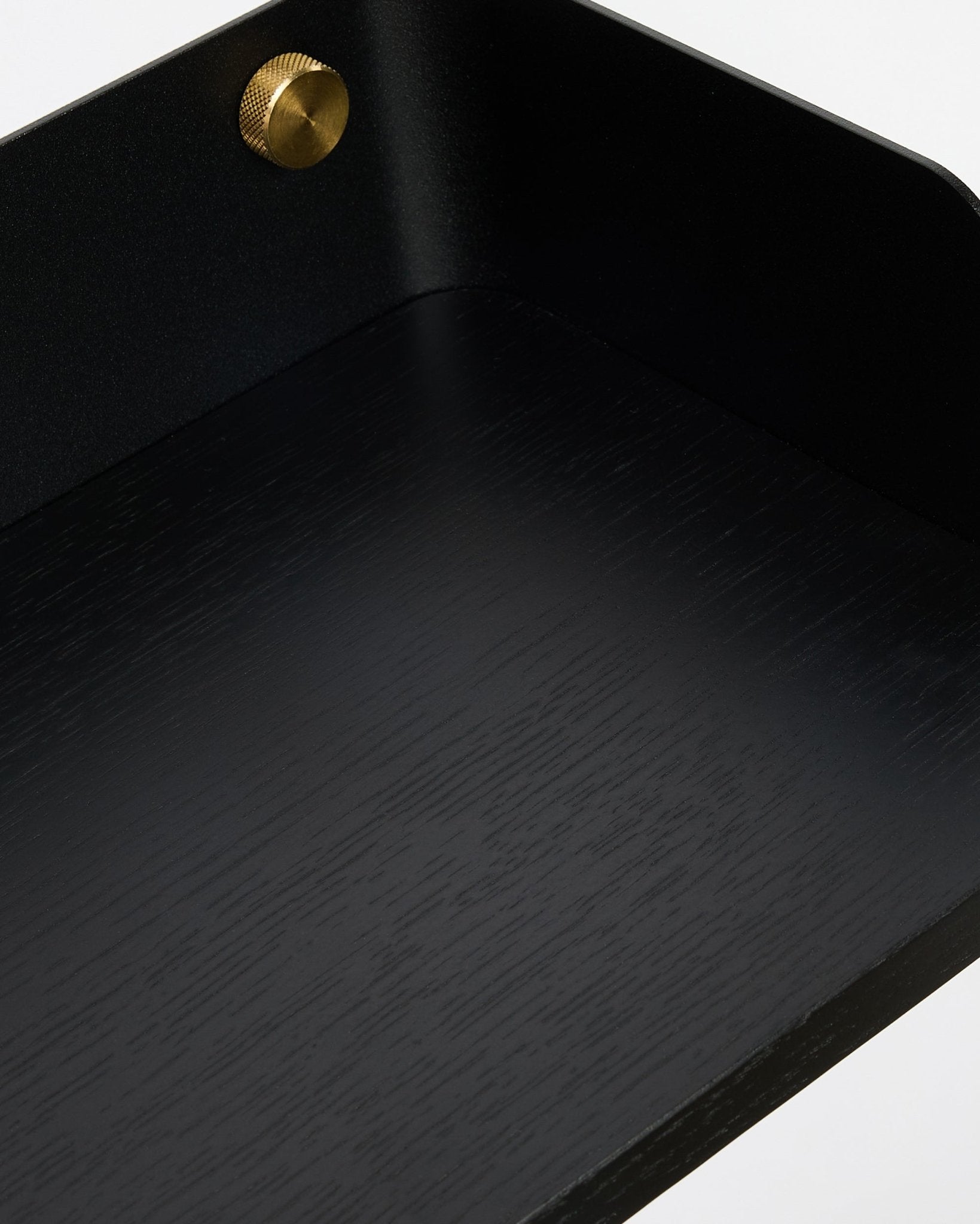 Zbliżenie na półkę na książki Linn marki WoodUpp w kolorze Black Oak (55,9 cm), pokazujące nordycką strukturę słojów drewna i detal złotej śruby, zaprojektowaną tak, by pasowała do kolekcji Akupanel.