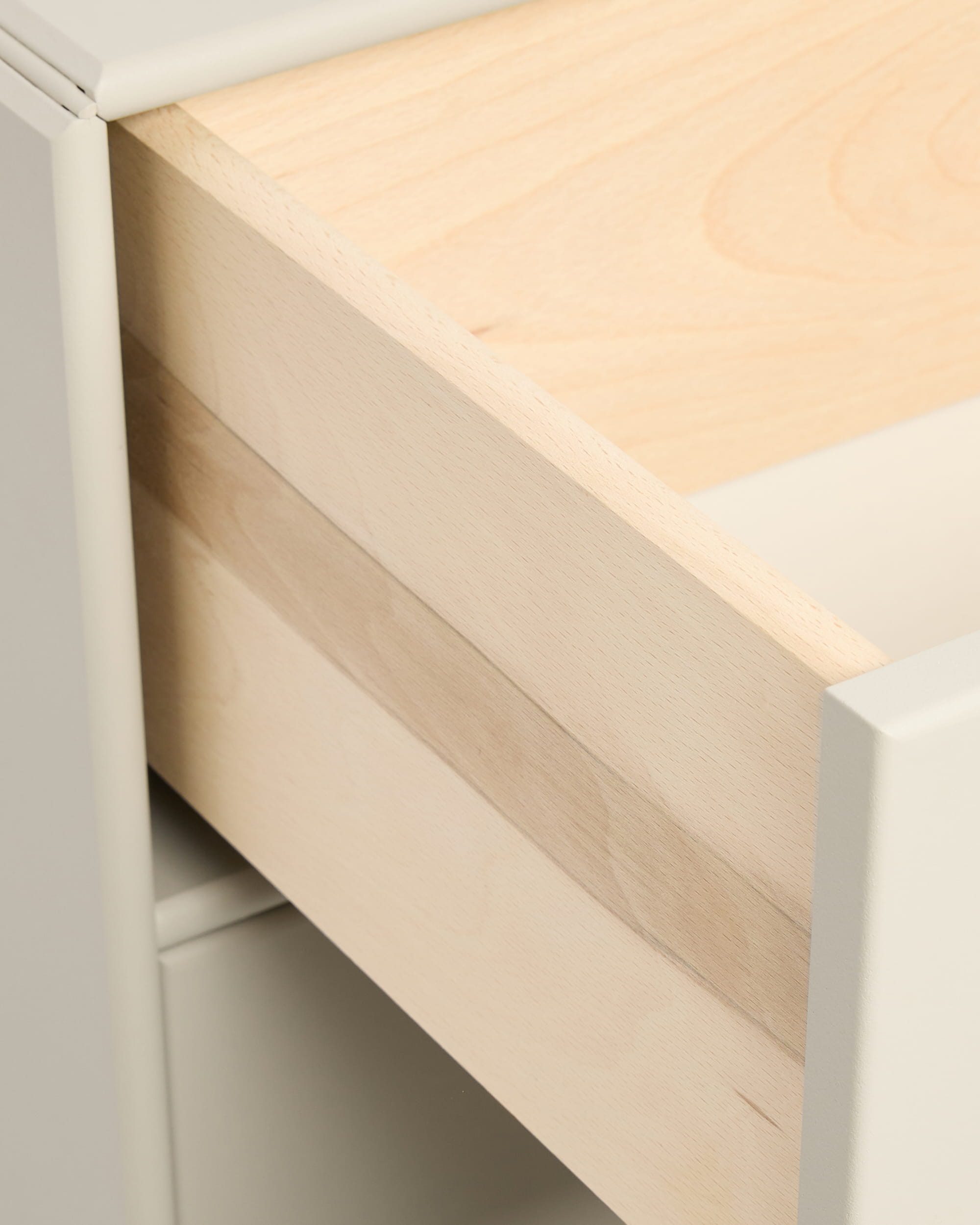 Zbliżenie na częściowo otwartą beżową szufladę Arka Bookcase marki WoodUpp w białej szafce, przedstawioną z uchwytami z kolekcji CREATE.