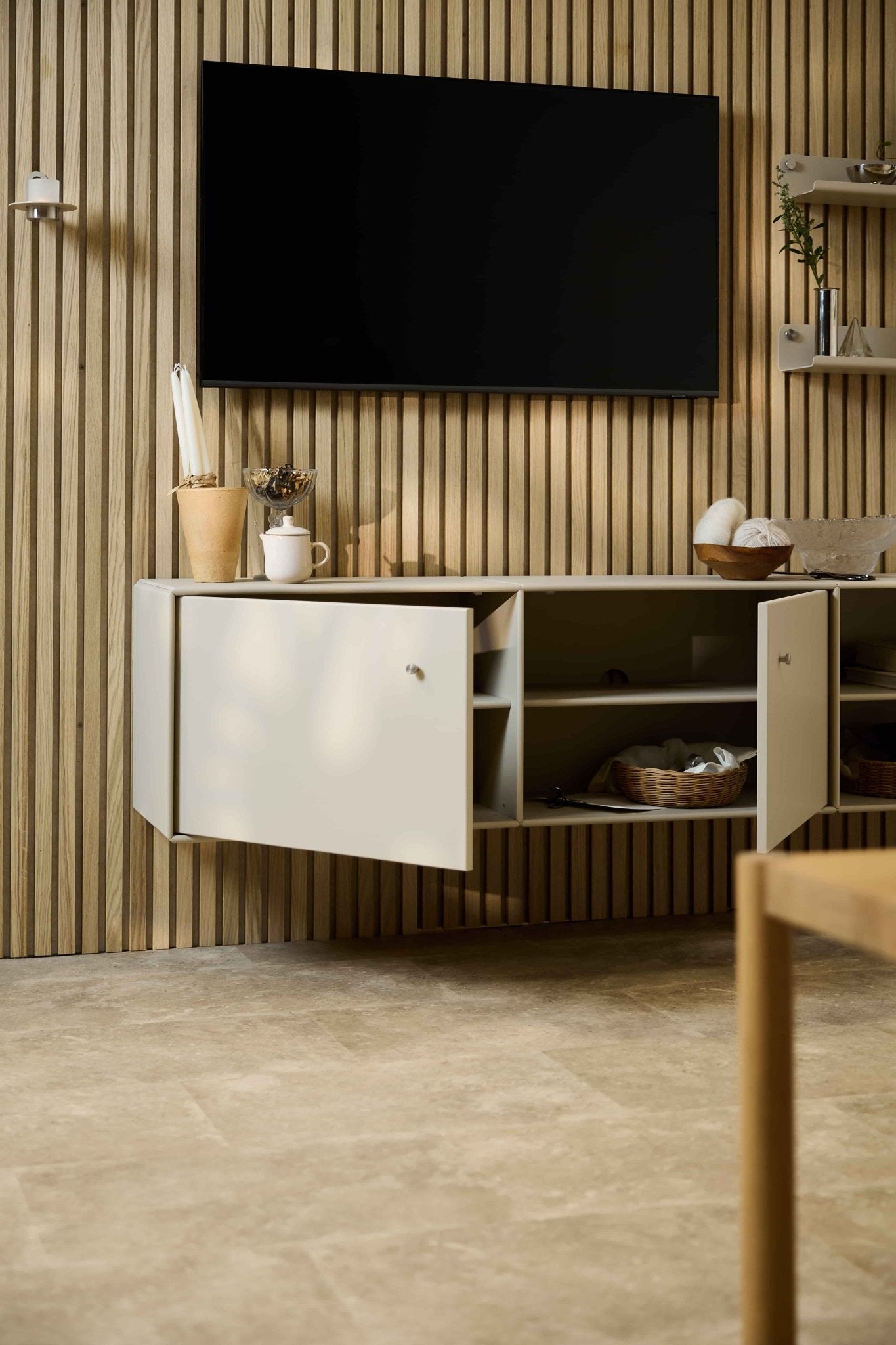 Nowoczesny salon z konsolą telewizyjną Arka w kolorze beżowym marki WoodUpp, umieszczoną pod szafką i telewizorem na ścianie z akustycznych drewnianych listew Akupanel w stylu skandynawskim. Meble modułowe.