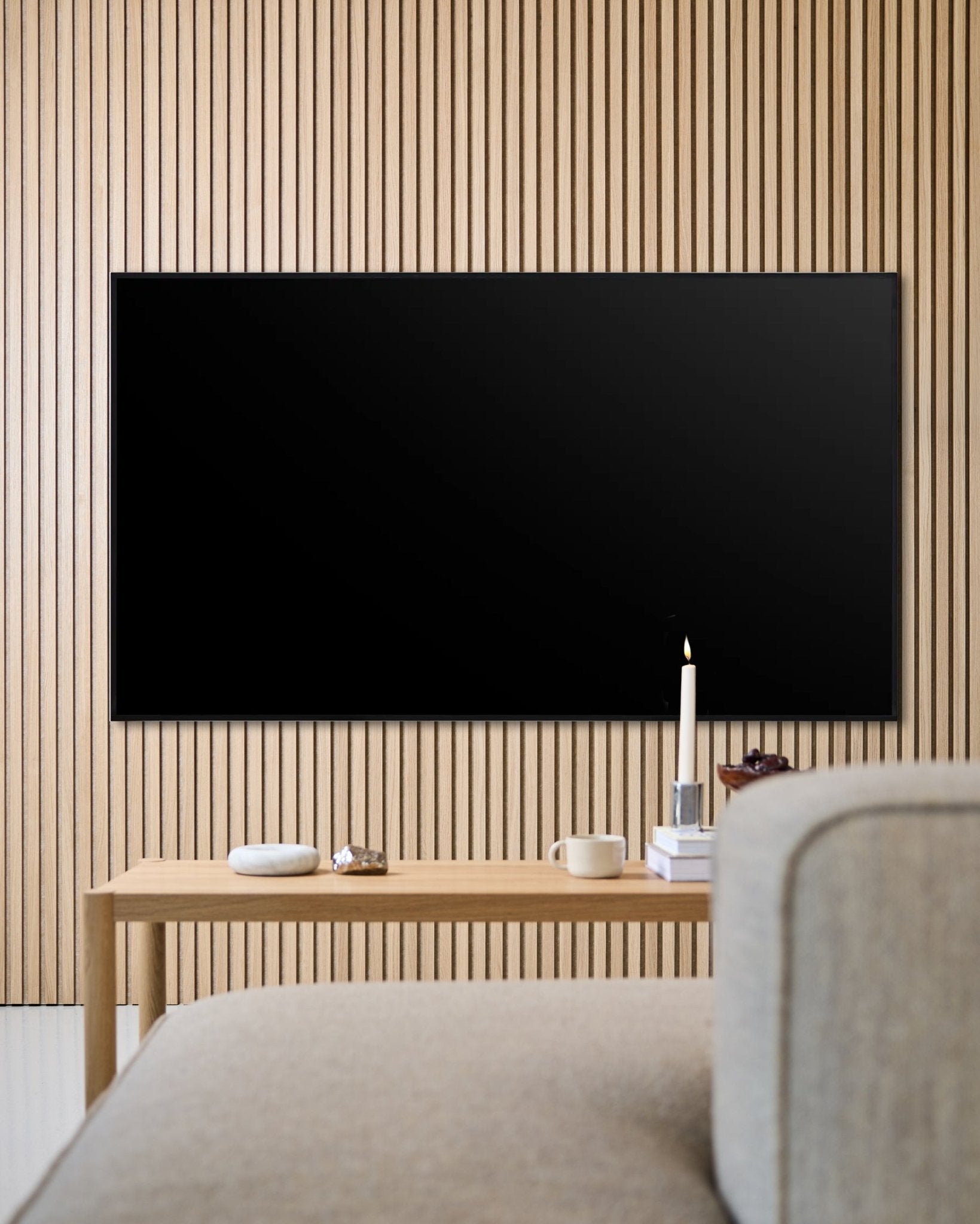 Nowoczesny salon z płaskim telewizorem zamontowanym na ścianie, Akupanel drewnianą ścianą z paneli akustycznych i drewnianym stolikiem kawowym, które tworzą przytulną atmosferę.