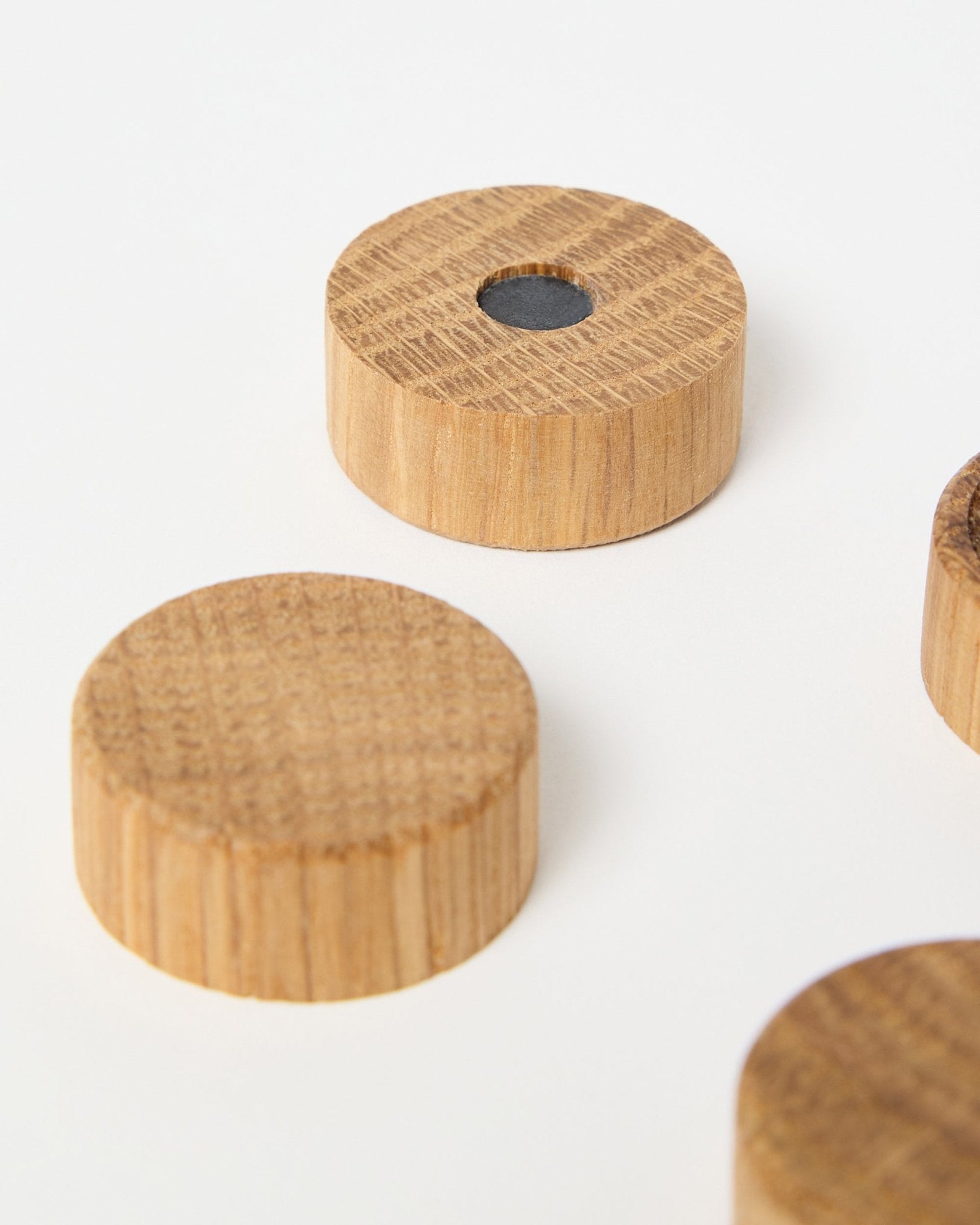 Zestaw czterech magnesów natural oak od WoodUpp, zaprojektowanych do użytku z akustycznymi panelami drewnianymi Akupanel, w tym jeden z centralnie umieszczonym magnesem neodymowym dla lepszej przyczepności, pokazany na białym tle.