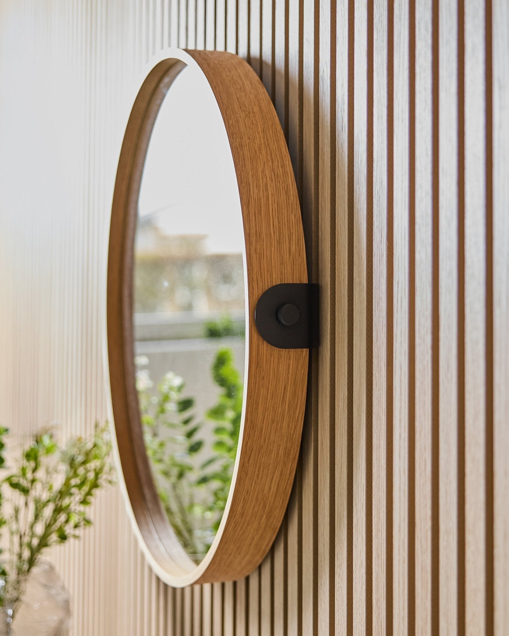 Linn | Mirror / Natural Oak od WoodUpp zamontowane na ścianie z pasiastym panelem Panel akustyczny, odbijające zieleń i naturalne światło z pobliskiego okna.