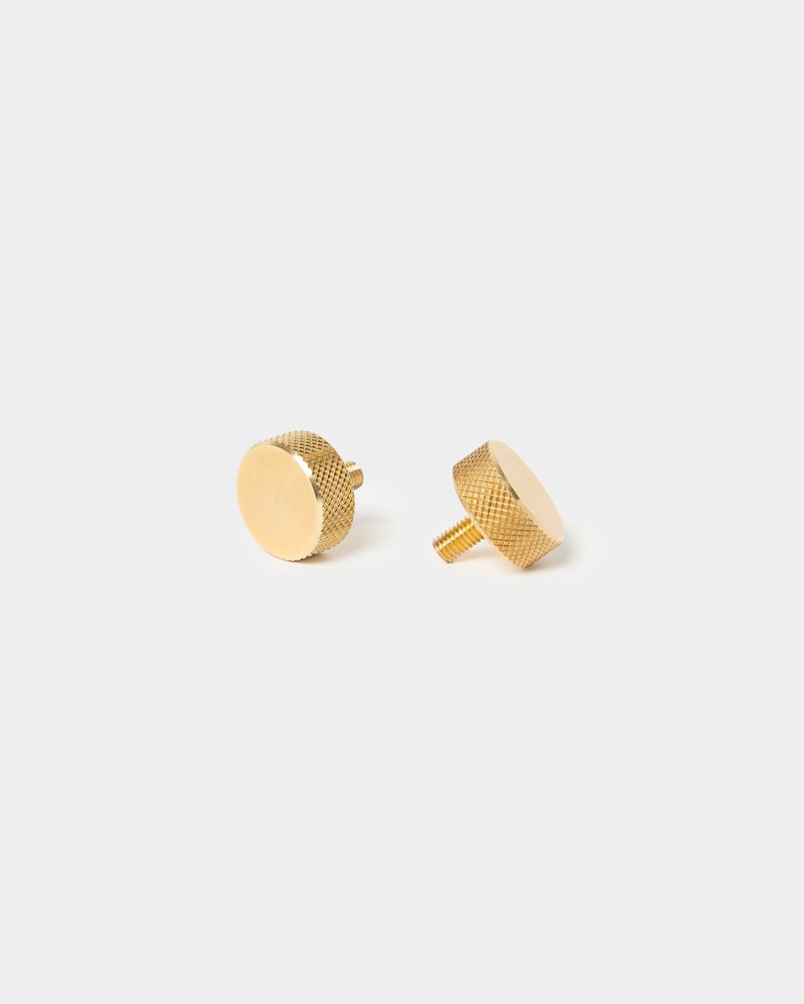 Para radełkowanych śrub WoodUpp brass (M5x10 mm, 20x8.8), z fakturowanymi krawędziami i krótkimi trzpieniami, przeznaczonych do akcesoriów Akupanel, na jasnym, jednolitym tle.