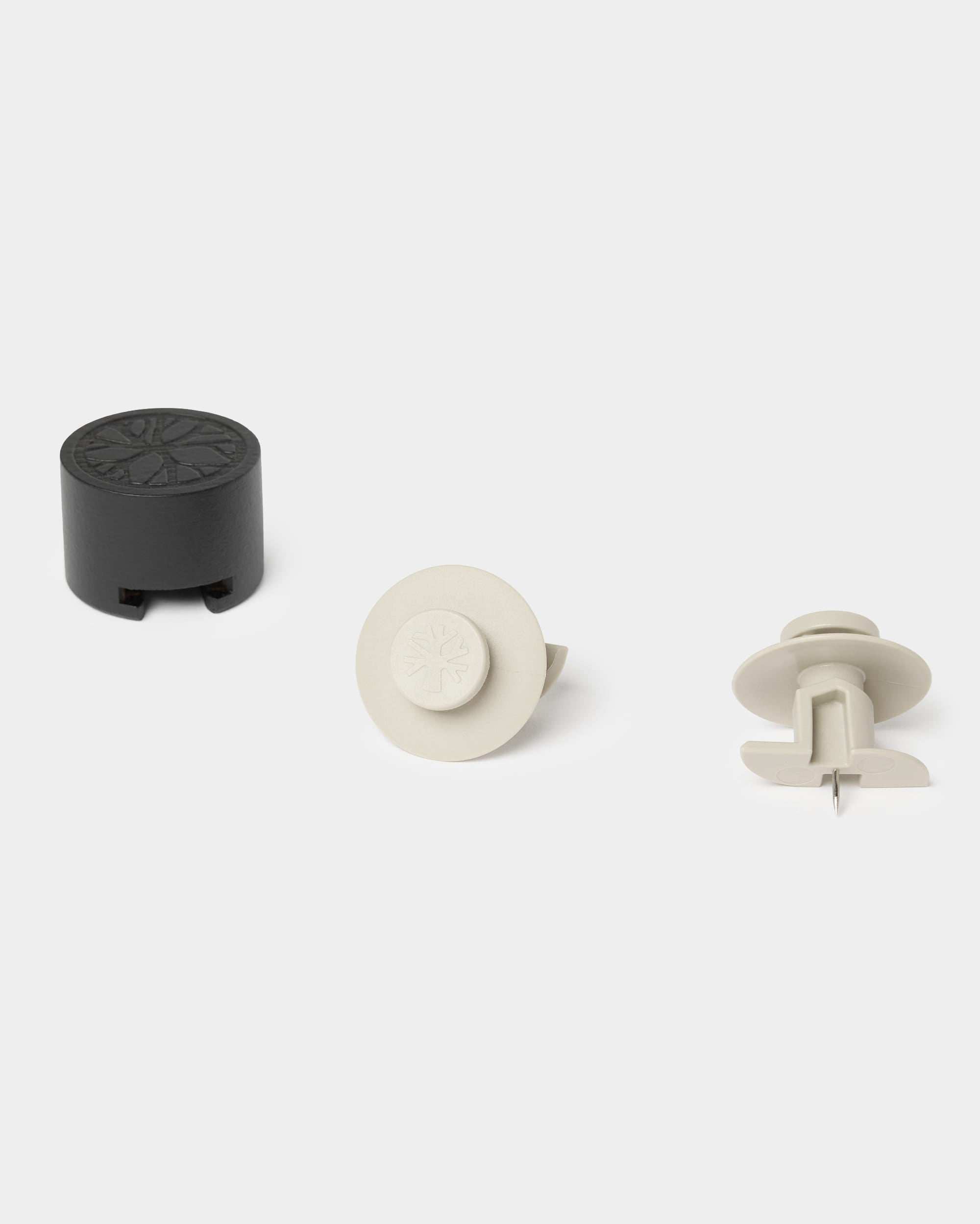 Trzy beżowe elementy mocujące do ścian Dupps firmy WoodUpp, pokazane pod różnymi kątami na jednolitym jasnym tle. Akcesoria do montażu paneli akustycznych Akupanel.