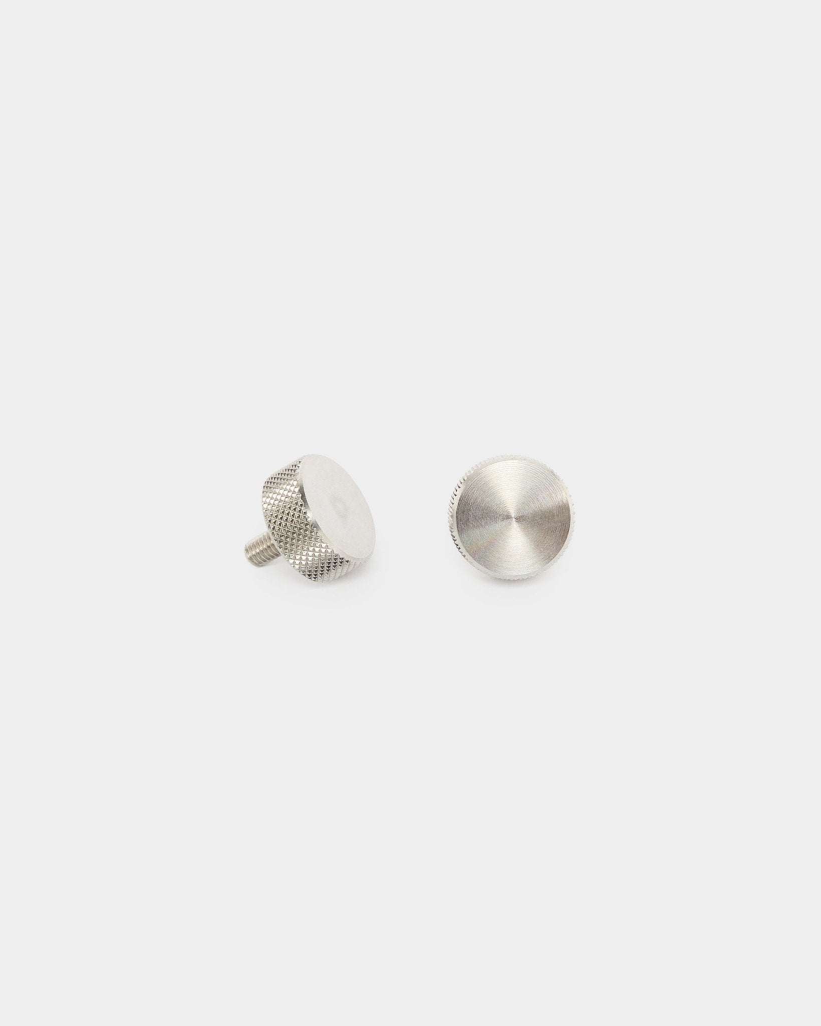 Dwa śruby radełkowane WoodUpp ze stali nierdzewnej steel (M5x10 mm, 20x8.8), akcesoria do paneli akustycznych Akupanel, pokazane w pozycji stojącej i na płasko na jednolitym białym tle.