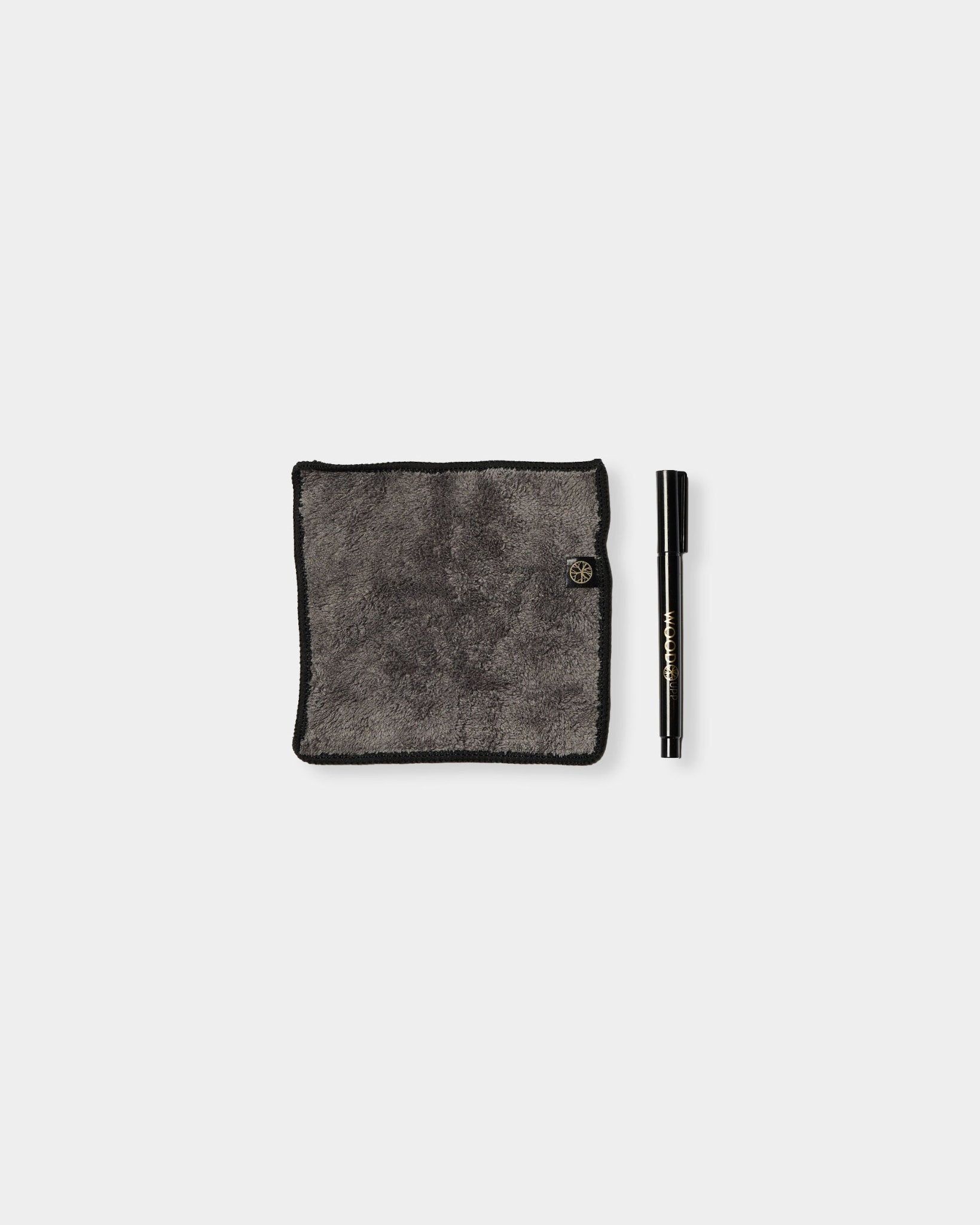 Zestaw Blackboard Norr od WoodUpp zawiera szarą ściereczkę z mikrofibry z krawędziami black oraz marker z tuszem kredowym, przeznaczony do użycia na magnetycznych panelach akustycznych.