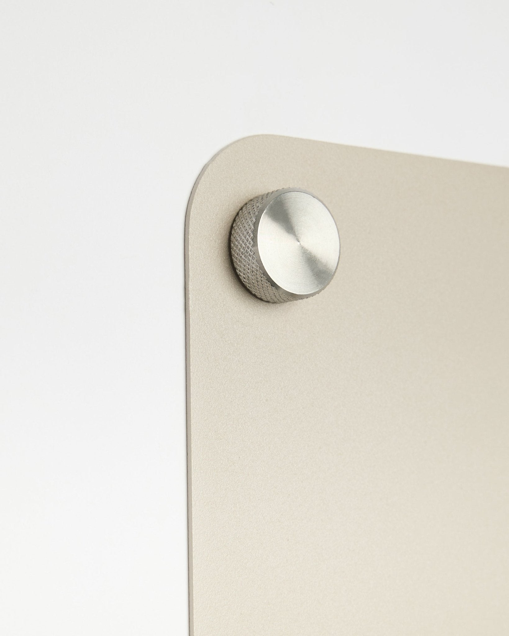 Zbliżenie na okrągły metalowy wieszak przymocowany do tablicy magnetycznej WoodUpp large beige Norr, z detalem z matowego szkła na białym tle.
