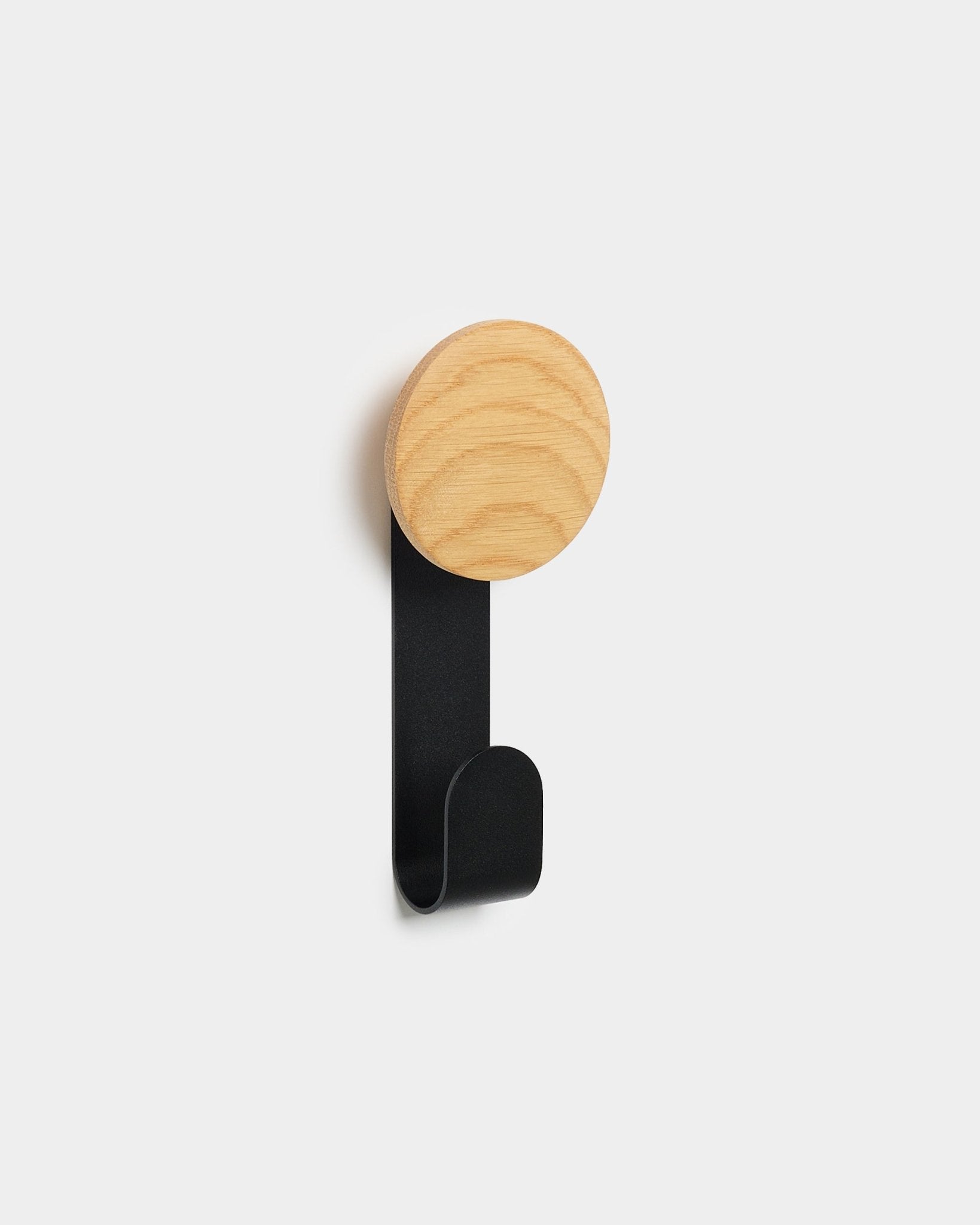 Wieszak Linn Vertical od WoodUpp ma okrągłą górną część z natural oak i black metalowy haczyk. Został zaprojektowany do wieszania akcesoriów na akustycznych panelach drewnianych Akupanel Nordic.