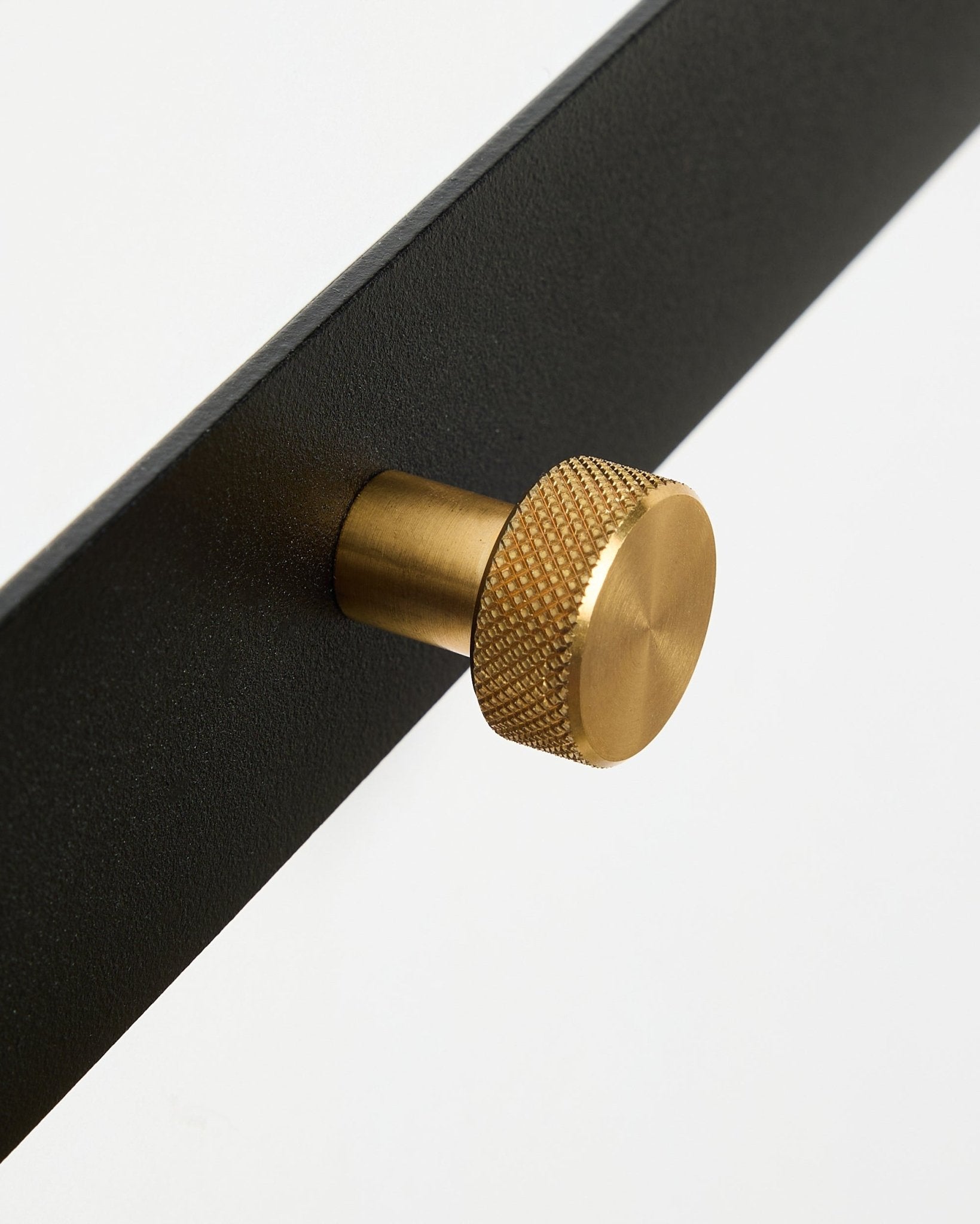 Zbliżenie na wieszak ścienny Norr Coat Hook Rack X5 od WoodUpp, z black malowaniem proszkowym steel i okrągłymi, fakturowanymi gałkami brass, na białym tle.