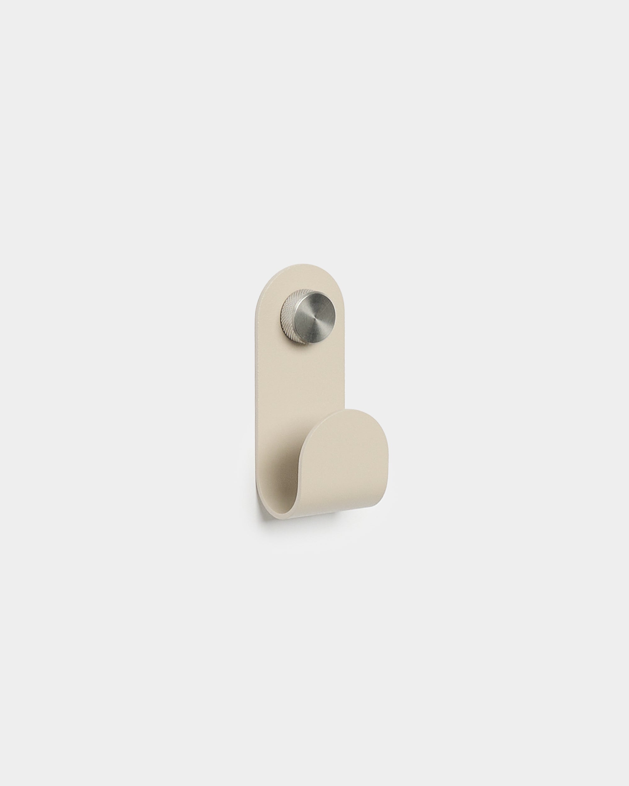 WoodUpp Norr Single Hanger w kolorze beige o minimalistycznym, zaokrąglonym kształcie i wykończeniu ze szczotkowanego metalu, zaprojektowany jako akcesorium do kompaktowych haczyków ściennych Akupanel.