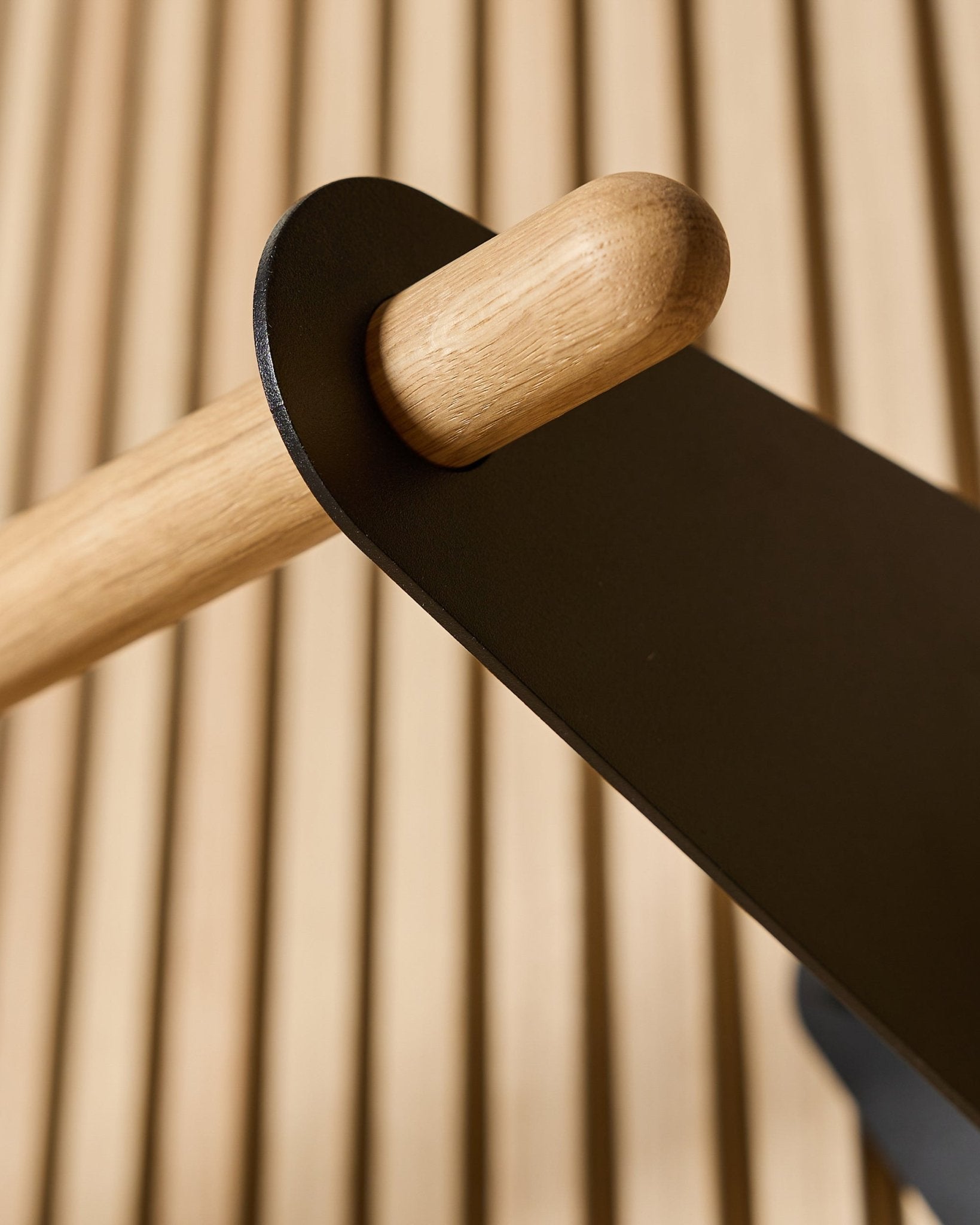 Zbliżenie na wieszak WoodUpp Linn Coat Rail w kolorze black, 75,9 cm, z drążkiem z litego dębu zamocowanym na metalowym wsporniku black na nordyckim akustycznym panelu ściennym z lamelami.
