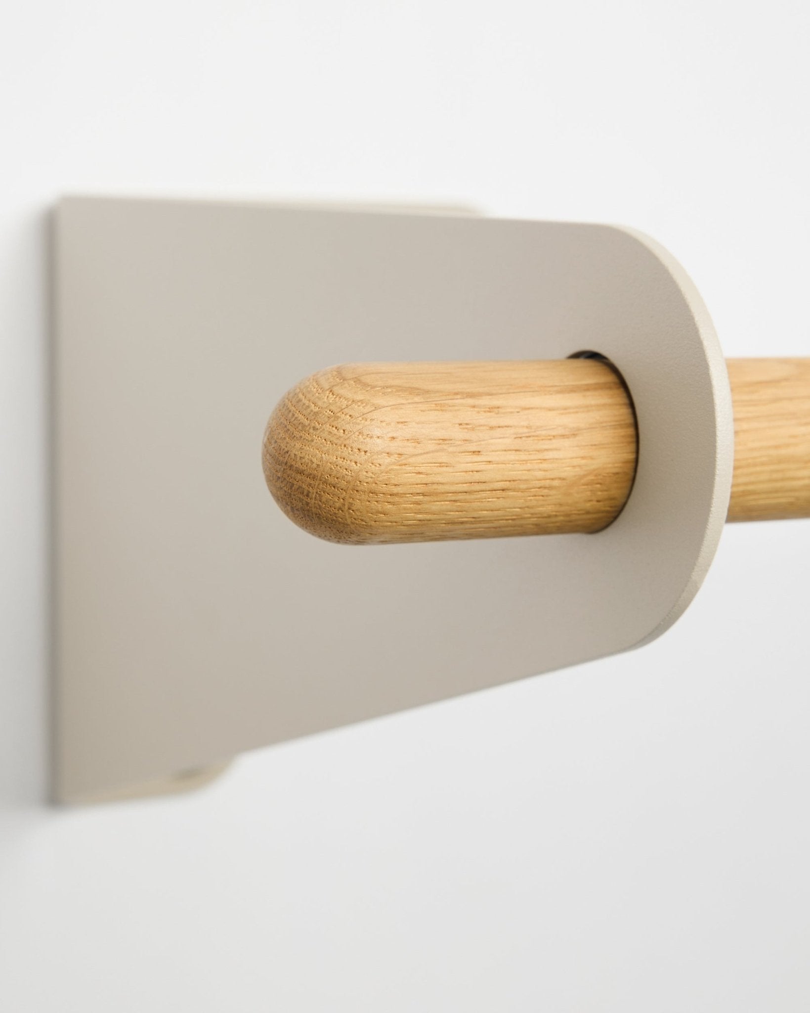 Zbliżenie na wieszak ścienny WoodUpp Linn w kolorze beige, 115,9 cm, z jasnym metalowym wspornikiem w kolorze beige, zamontowanym na białej ścianie. Dodatek w nordyckim, minimalistycznym stylu.