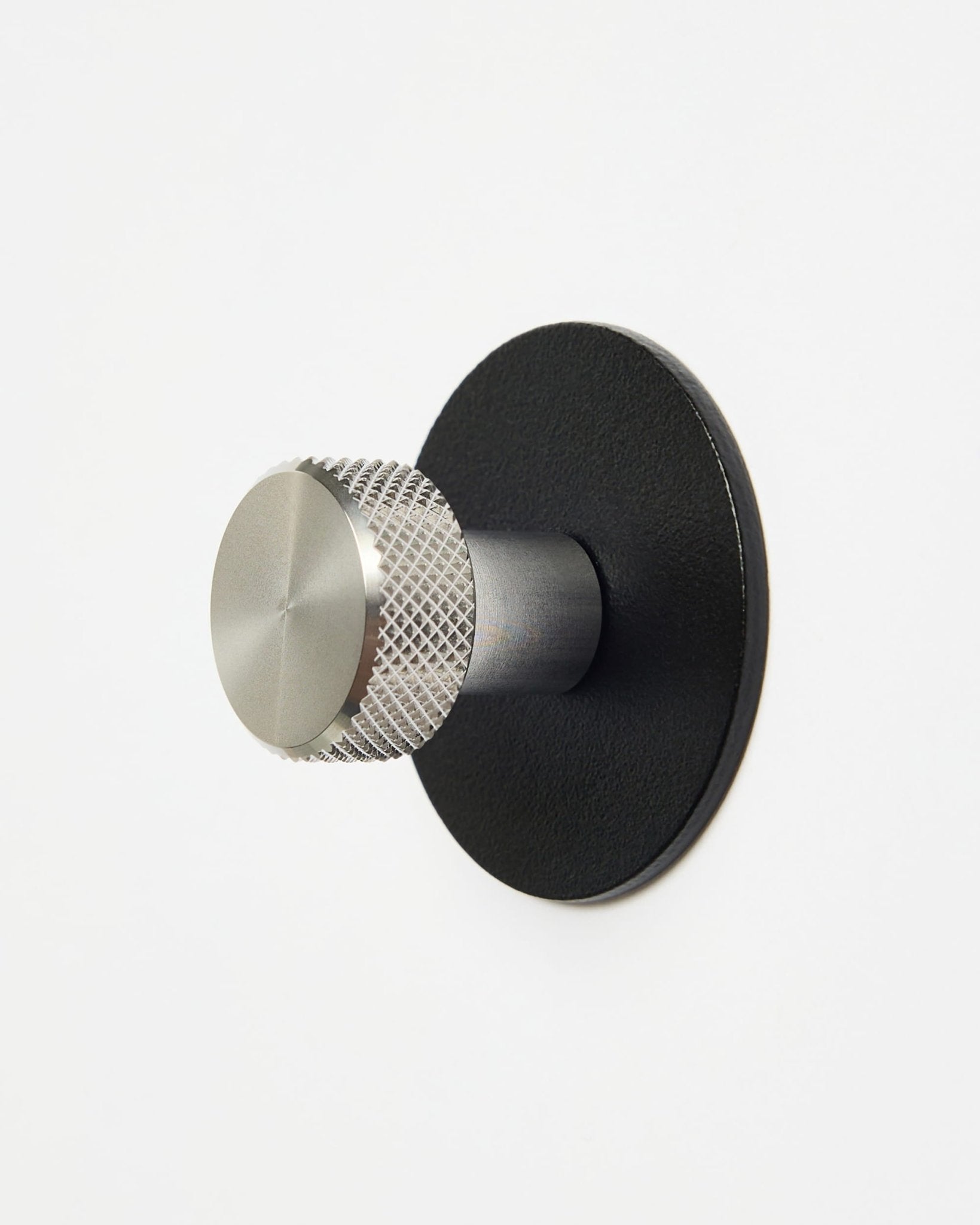 WoodUpp Norr | Coat Hook X1 w kolorze black i ze stali nierdzewnej steel, zamontowany na gładkiej białej ścianie, zaprojektowany jako akcesorium z kolekcji CREATE do systemów Akupanel.