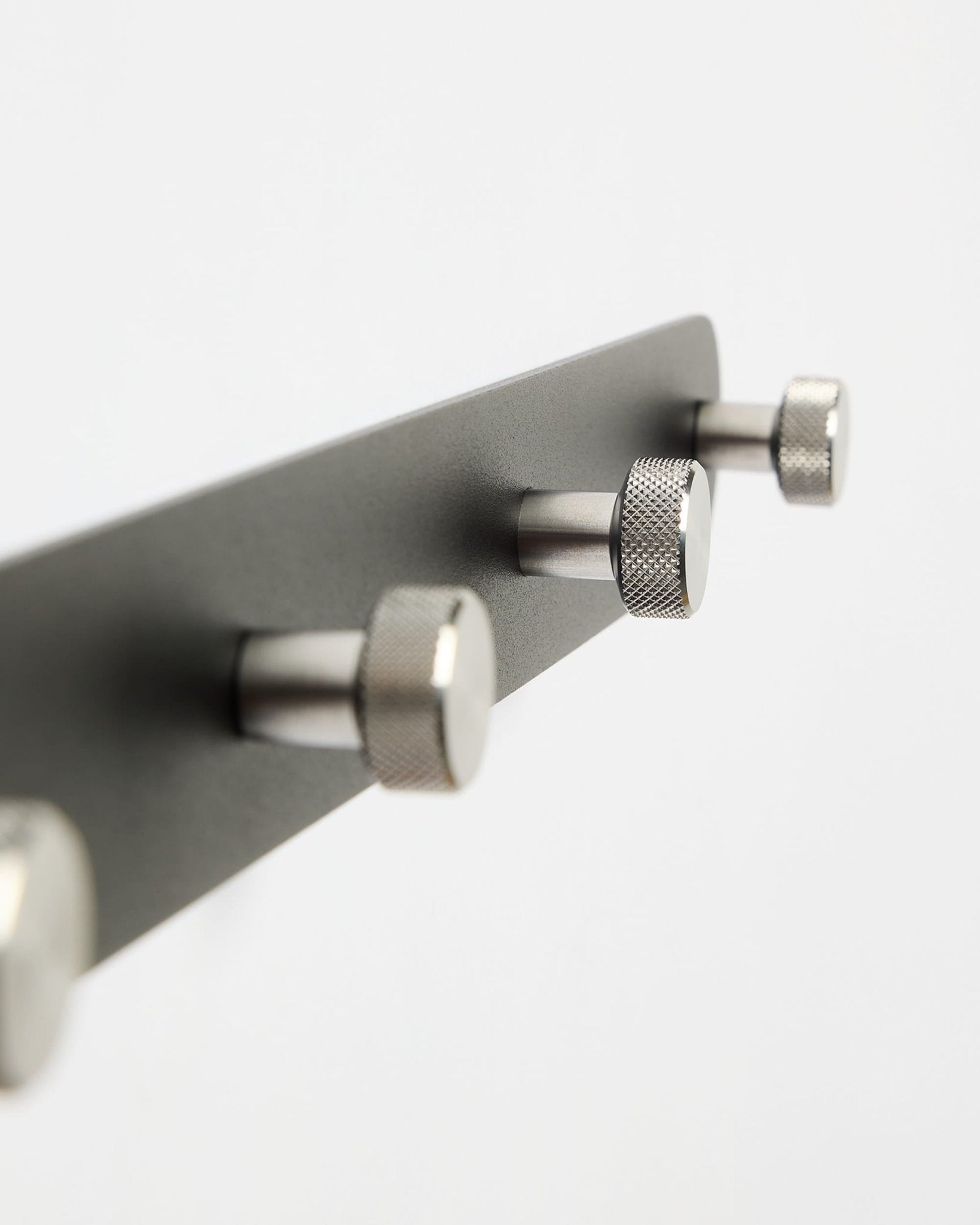 Wieszak ścienny WoodUpp Norr Coat Hook Rack X7 w kolorze czarnym i ze stali nierdzewnej, z siedmioma haczykami, pokazany na gładkim białym tle; część kolekcji akcesoriów CREATE.