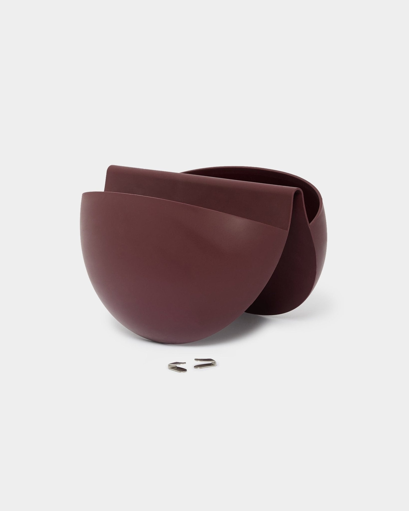 Dwie doniczki WoodUpp Gro Soft Pocket BM2 w kolorze Ox Red, o pojemności 4 l, stoją obok siebie, każda wyposażona w metalowy hak ścienny do montażu na panelach akustycznych.