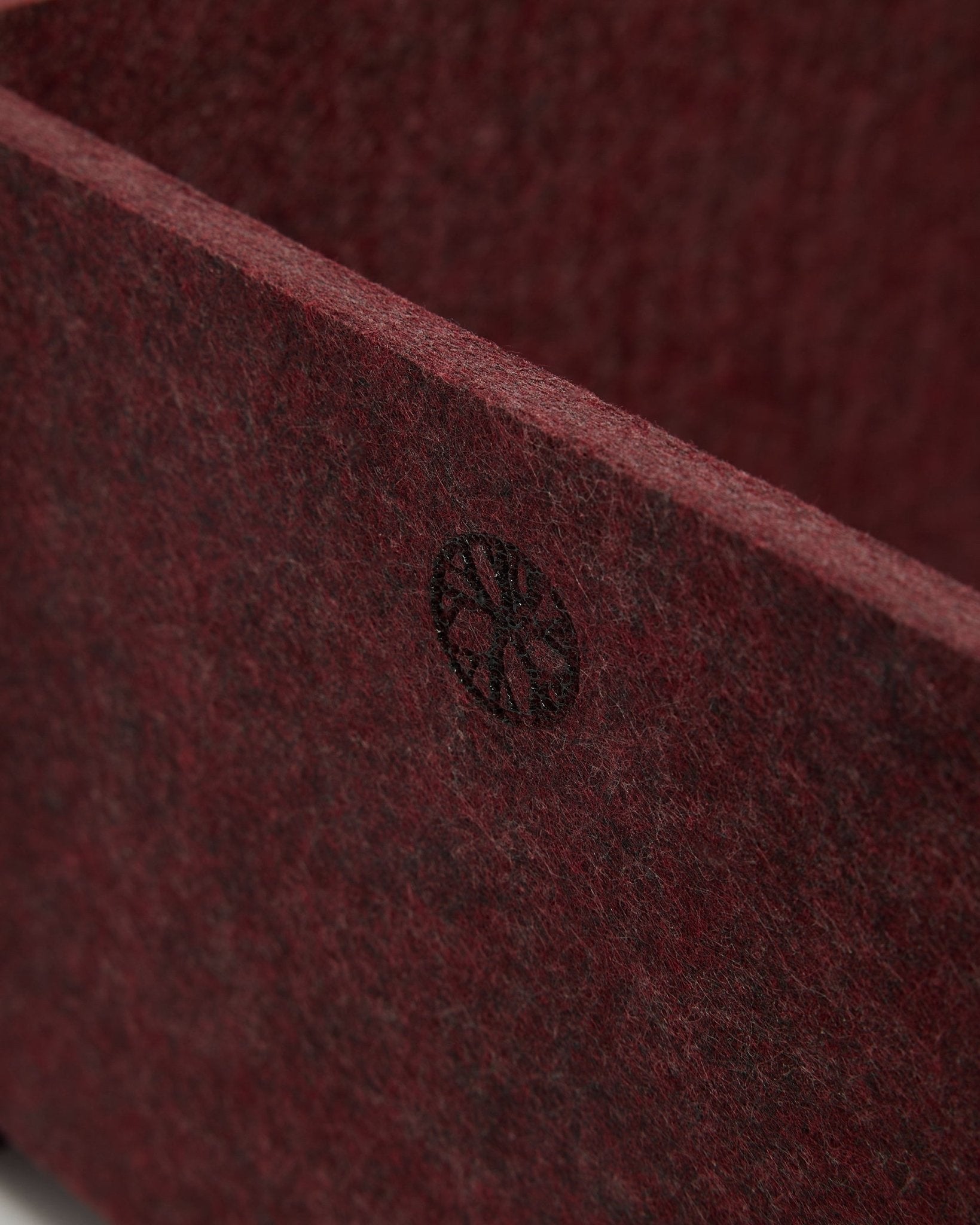 Zbliżenie na WoodUpp Vigg | Felt Box / BM2 w kolorze ox red, pokazujące teksturowany filc PET i okrągły emblemat black w rogu. Nordycki design akcesoriów akustycznych.