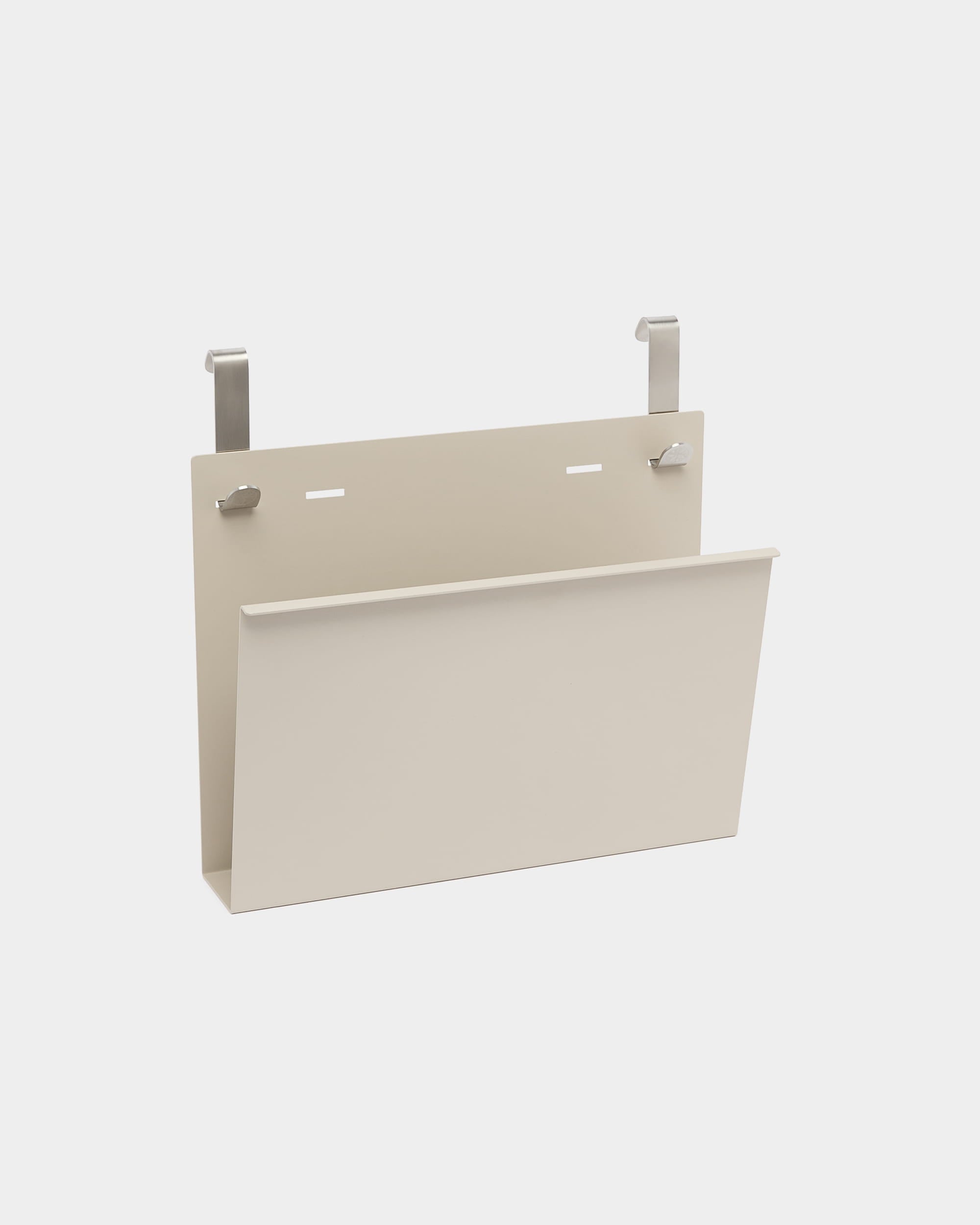 Nell Magazine Storage od WoodUpp to beige uchwyt na czasopisma z malowanego proszkowo steel, z dwoma srebrnymi haczykami do zawieszenia na akustycznych ściankach działowych lub przegrodach Nordic.