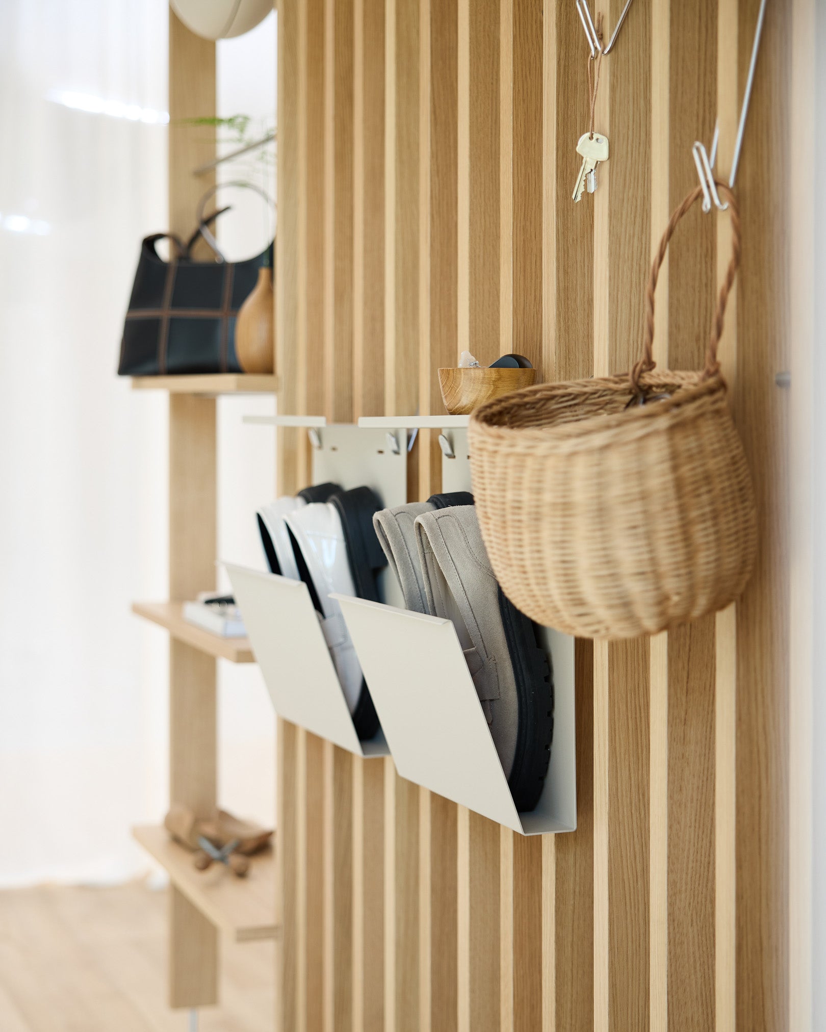 Nowoczesny przedpokój z WoodUpp beige Nell Shoe Storage, ścianami z akustycznych paneli drewnianych w kolorze Akupanel, haczykami ściennymi, wiszącym koszem i półką z dekoracjami.
