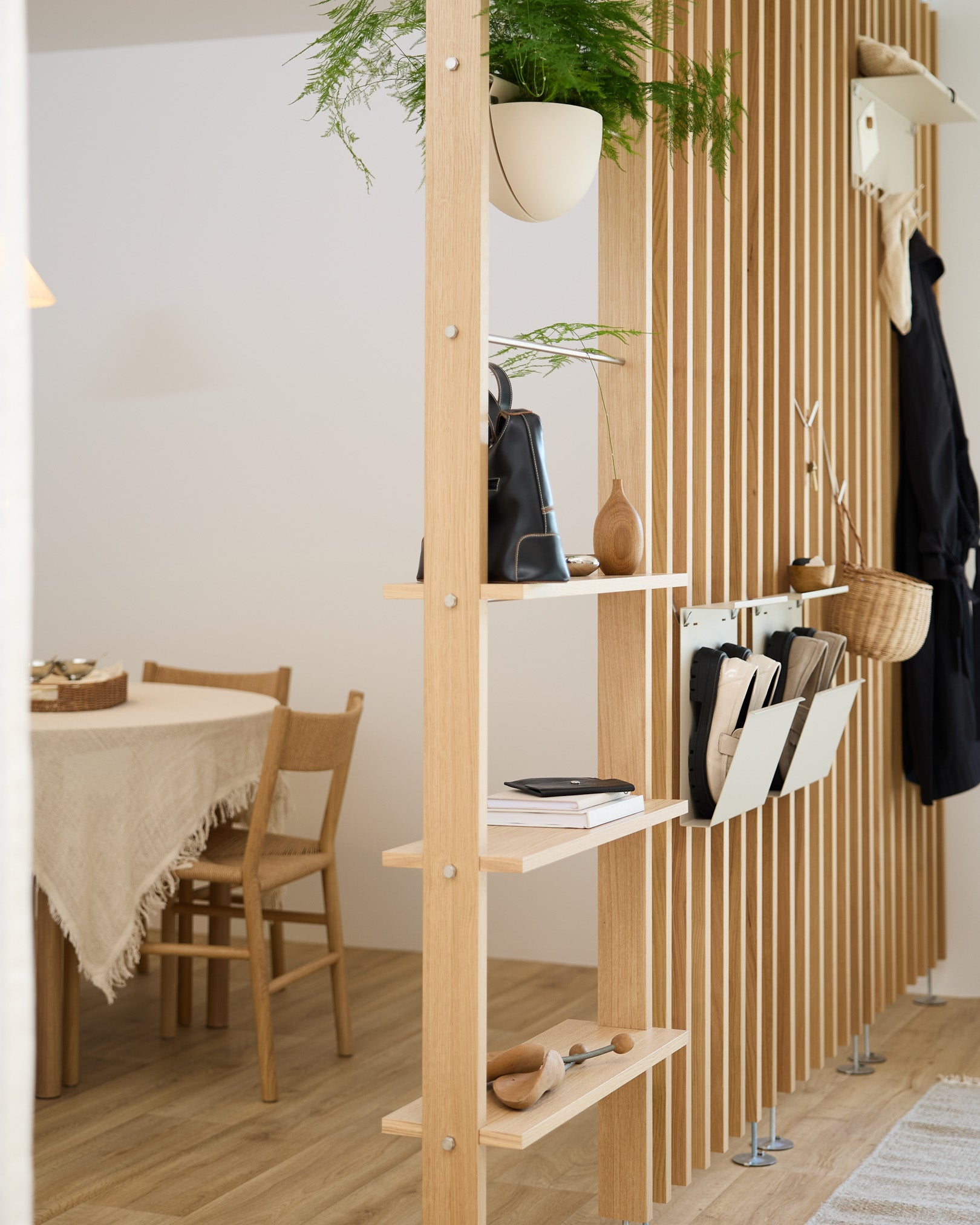 Otwarte drewniane półki oddzielają jadalnię, a Nell Shoe Storage w kolorze beige od WoodUpp pomaga zorganizować miejsce na buty w nowoczesnym nordyckim domu.