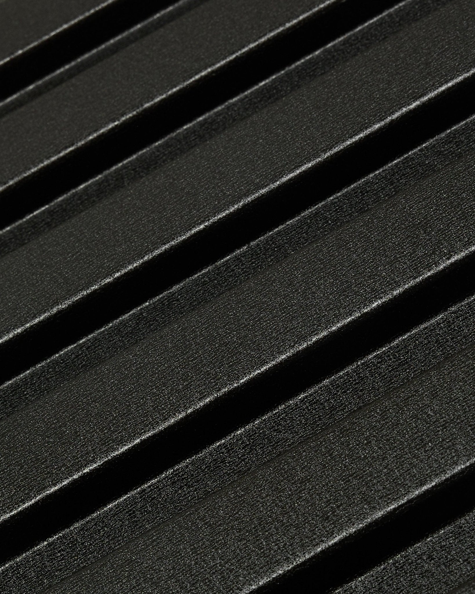 Zbliżenie na zewnętrzny panel elewacyjny Aluwood od WoodUpp: ciemna, fakturowana powierzchnia z aluminium z recyklingu z ukośnymi wypukłymi przetłoczeniami, o wymiarach 240 x 45,1 cm.