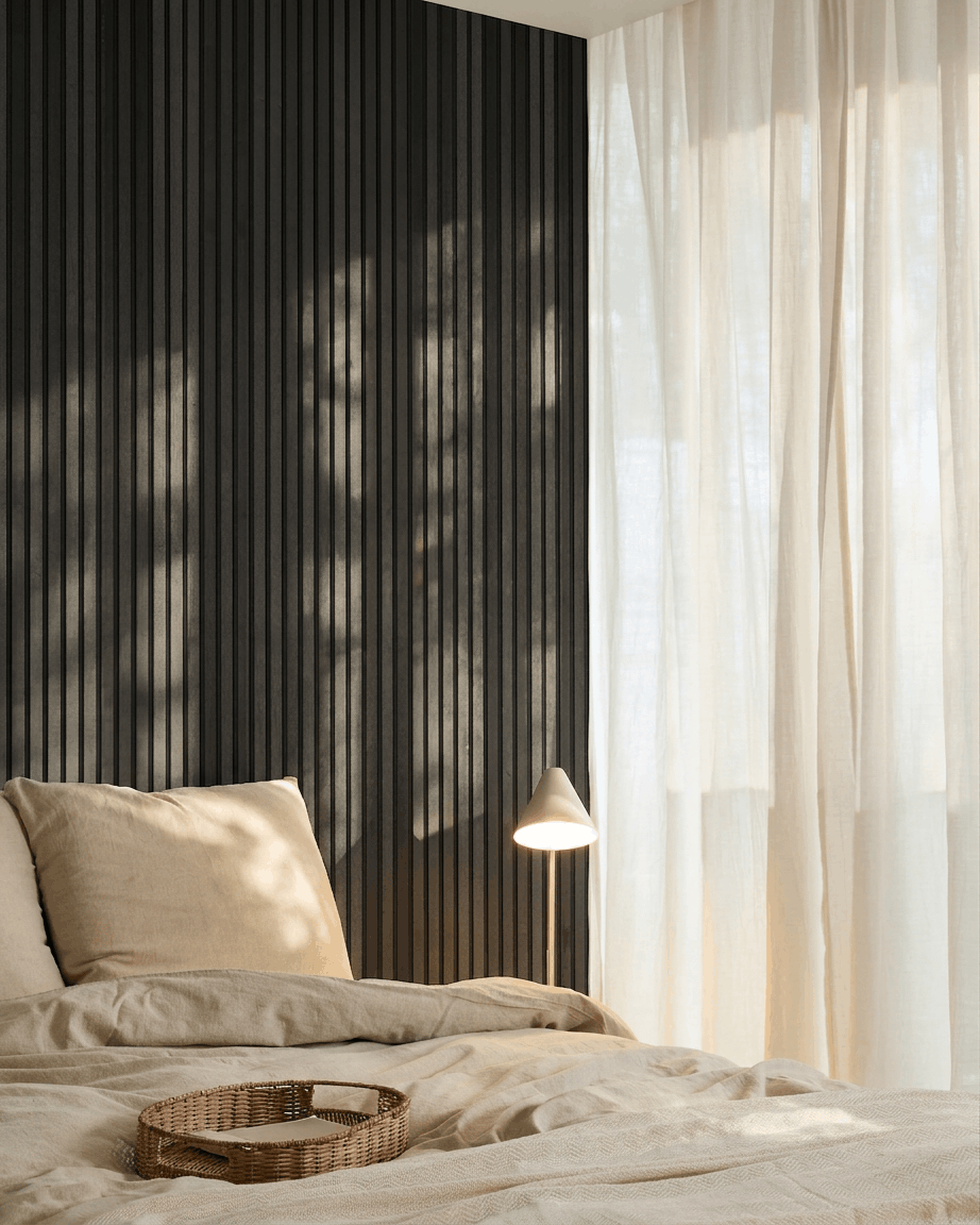 Minimalistyczna nordycka sypialnia z WoodUpp Akupanel Panel akustyczny w wykończeniu Black Ash, pościelą beige, wiklinową tacą i lekkimi zasłonami przepuszczającymi naturalne światło.