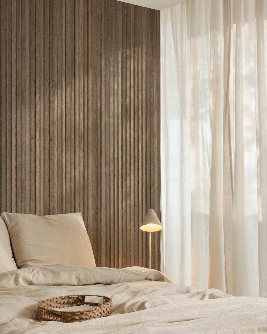 Minimalistyczna sypialnia z pościelą beige, wiklinową tacą, akustycznym panelem listwowym WoodUpp Akupanel Rustic Grey Oak, białą lampą i lekkimi zasłonami.