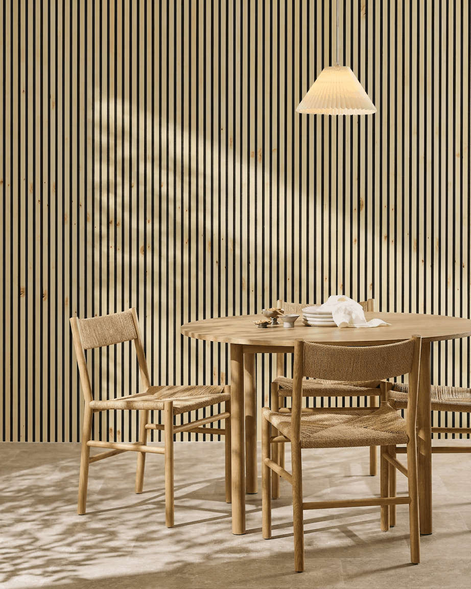 Panel akustyczny WoodUpp Akupanel, dostępny w wersji z naturalnego drewna, w kolorze alpejskim oraz z czarnym filcem, nadaje skandynawskiej jadalni z stołem i krzesłami ciepły, minimalistyczny akcent w stylu nordyckim.