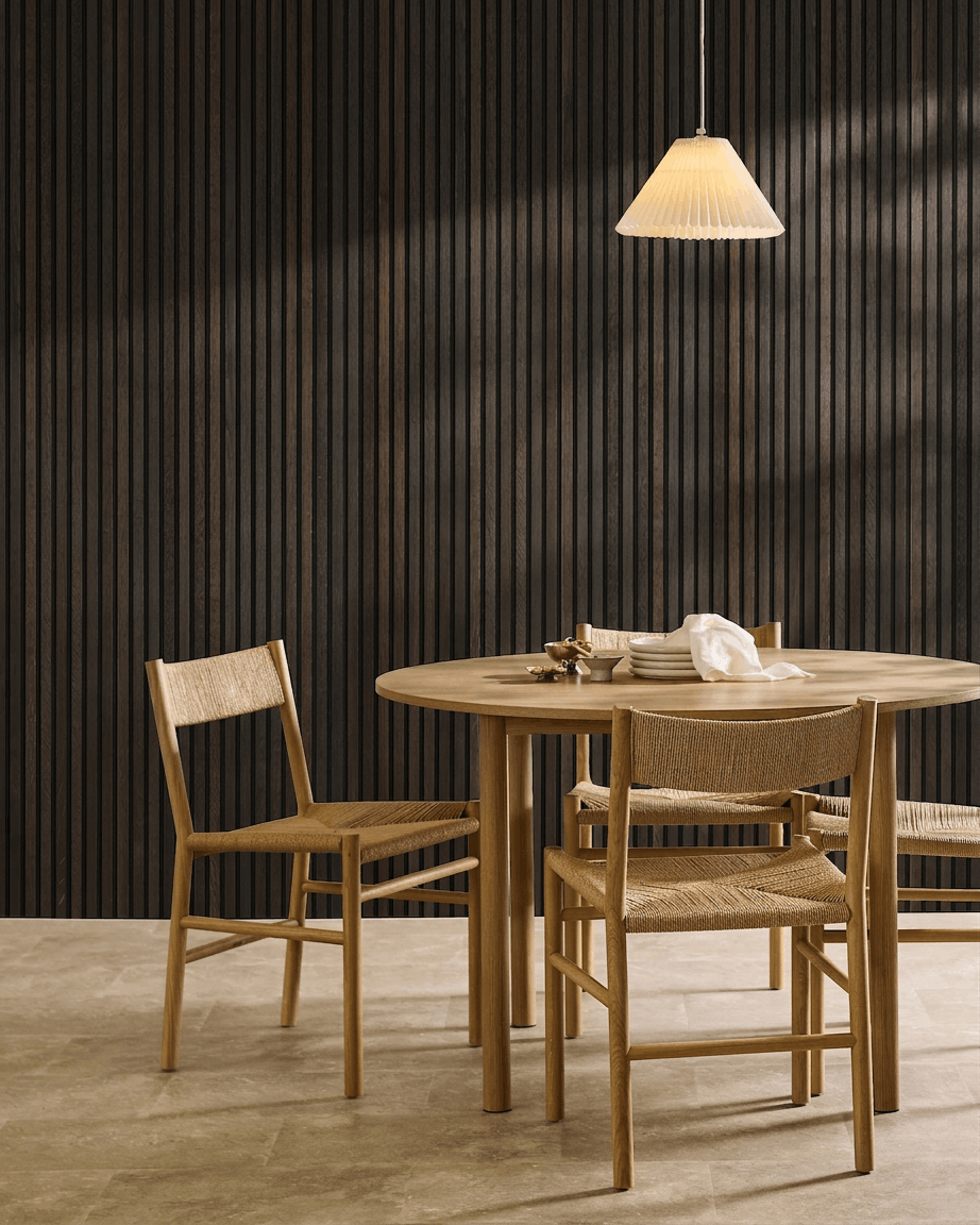 Minimalistyczna jadalnia z drewnianym stołem, skandynawskimi krzesłami, lampą wiszącą i akustycznym panelem lamelowym WoodUpp Akupanel Rustic Smoked Oak.