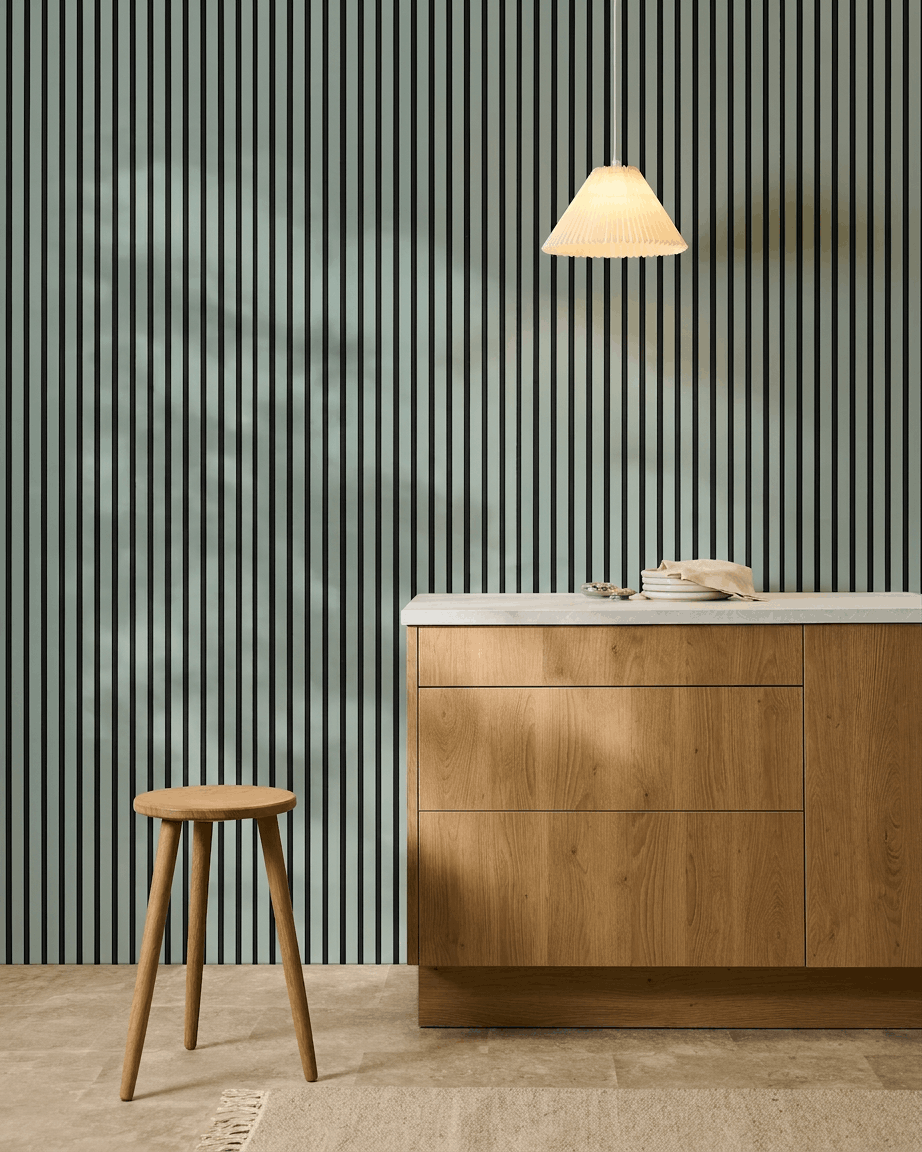 Minimalistyczna kuchnia w stylu nordyckim z drewnianym stołkiem, szafką i WoodUpp Akupanel Panel akustyczny w kolorze Cloud z filcem black (240x60 cm) dla komfortu akustycznego.
