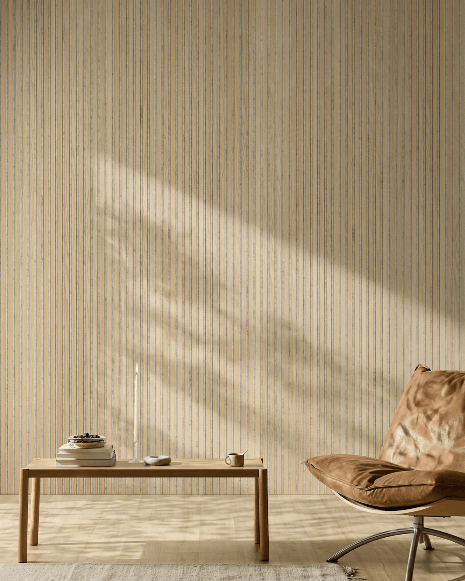 Minimalistyczne wnętrze z jasnobrązowym skórzanym fotelem, drewnianym stolikiem i świecą. Panel akustyczny WoodUpp Akupanel Classic Oak w formie ściany lamelowej dodaje nordyckiego stylu i komfortu akustycznego.