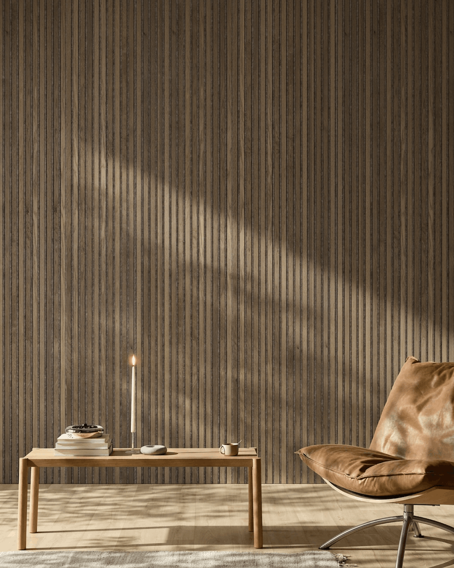 Nowoczesne wnętrze z fotelem z brown skóry, drewnianym stolikiem oraz panelem WoodUpp Akupanel w wykończeniu Rustic Grey Oak zamontowanym na ścianie, oświetlonym miękkim światłem słonecznym.