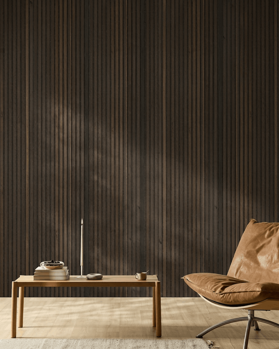 Minimalistyczne nordyckie wnętrze z krzesłem z jasnobrązowej skóry, drewnianym stolikiem, świecą i filiżanką na tle ściany WoodUpp Akupanel Natural Wood Rustic Smoked Oak Panel akustyczny.