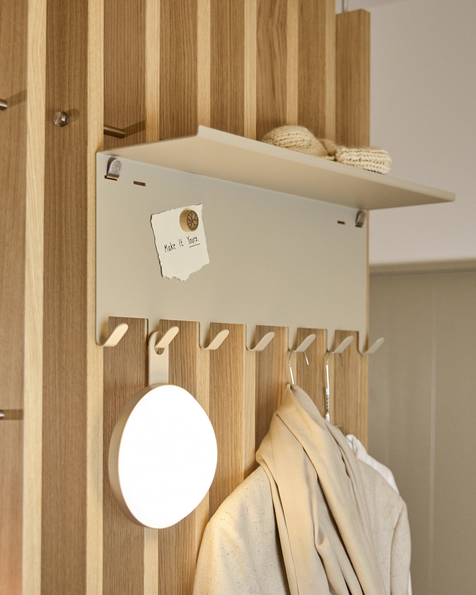 WoodUpp Nell | wieszak BM1 w kolorze beige (63,5 x 24 cm), z haczykami steel i półką, na której leżą dzianiny oraz notatka z napisem embrace BM1.
