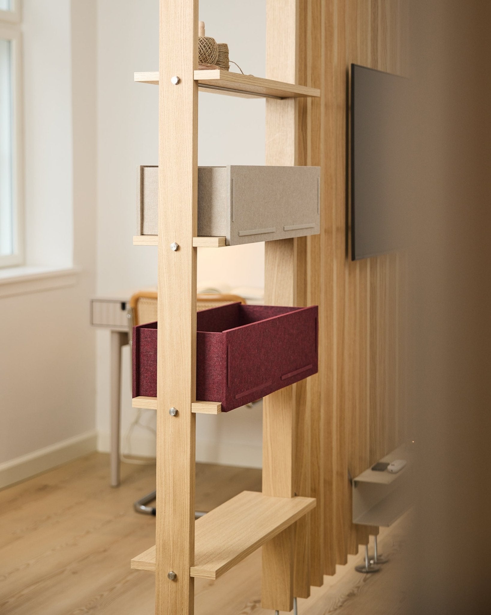 Półka WoodUpp eksponuje pudełko do przechowywania beige oraz ox red Vigg Felt Box / BM2 w jasnym, minimalistycznym nordyckim wnętrzu z akustycznymi detalami z drewna.
